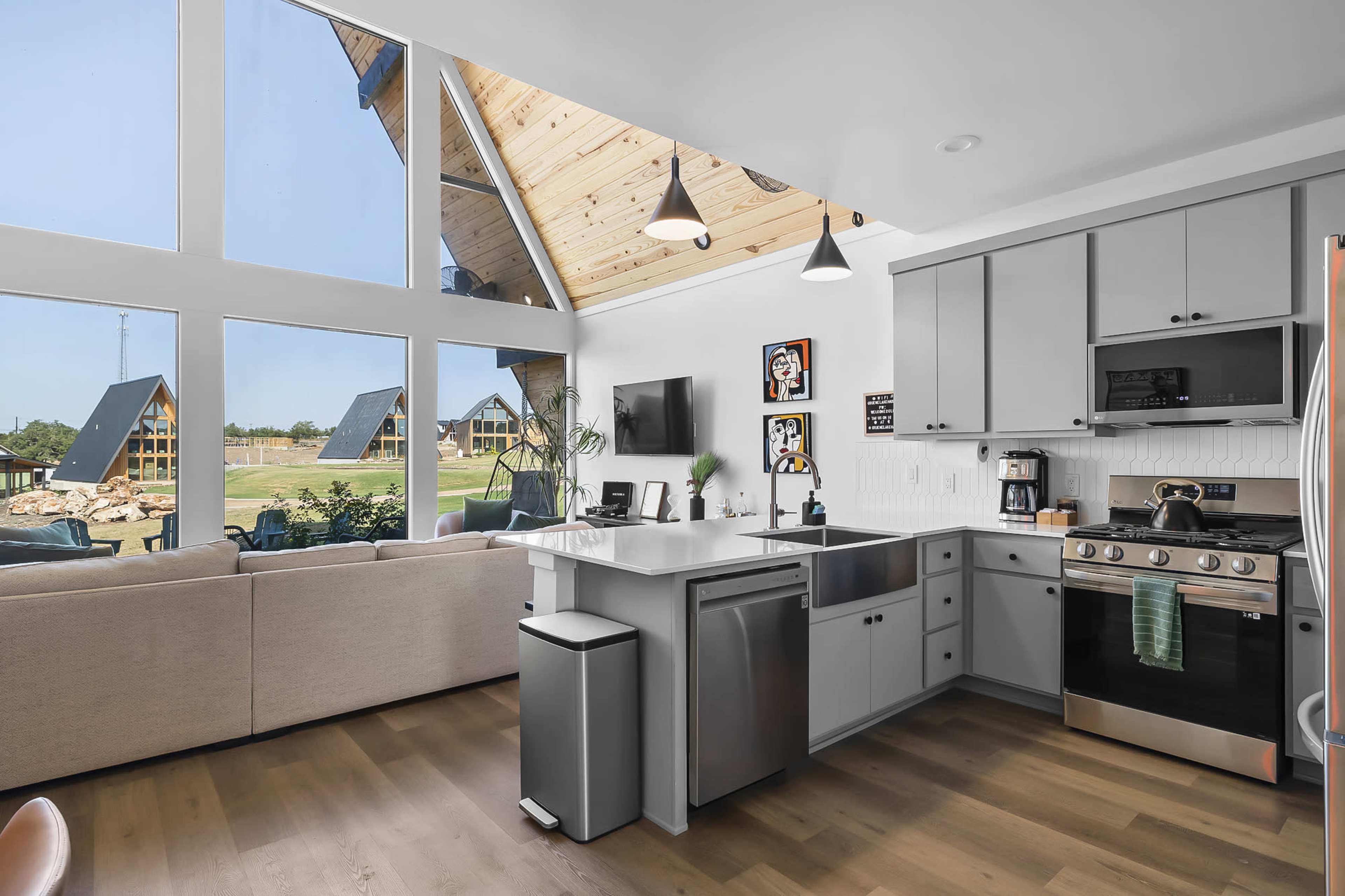 A modern kitchen with stainless steel appliances and large windows that provide natural light, overlooking a landscaped outdoor area.