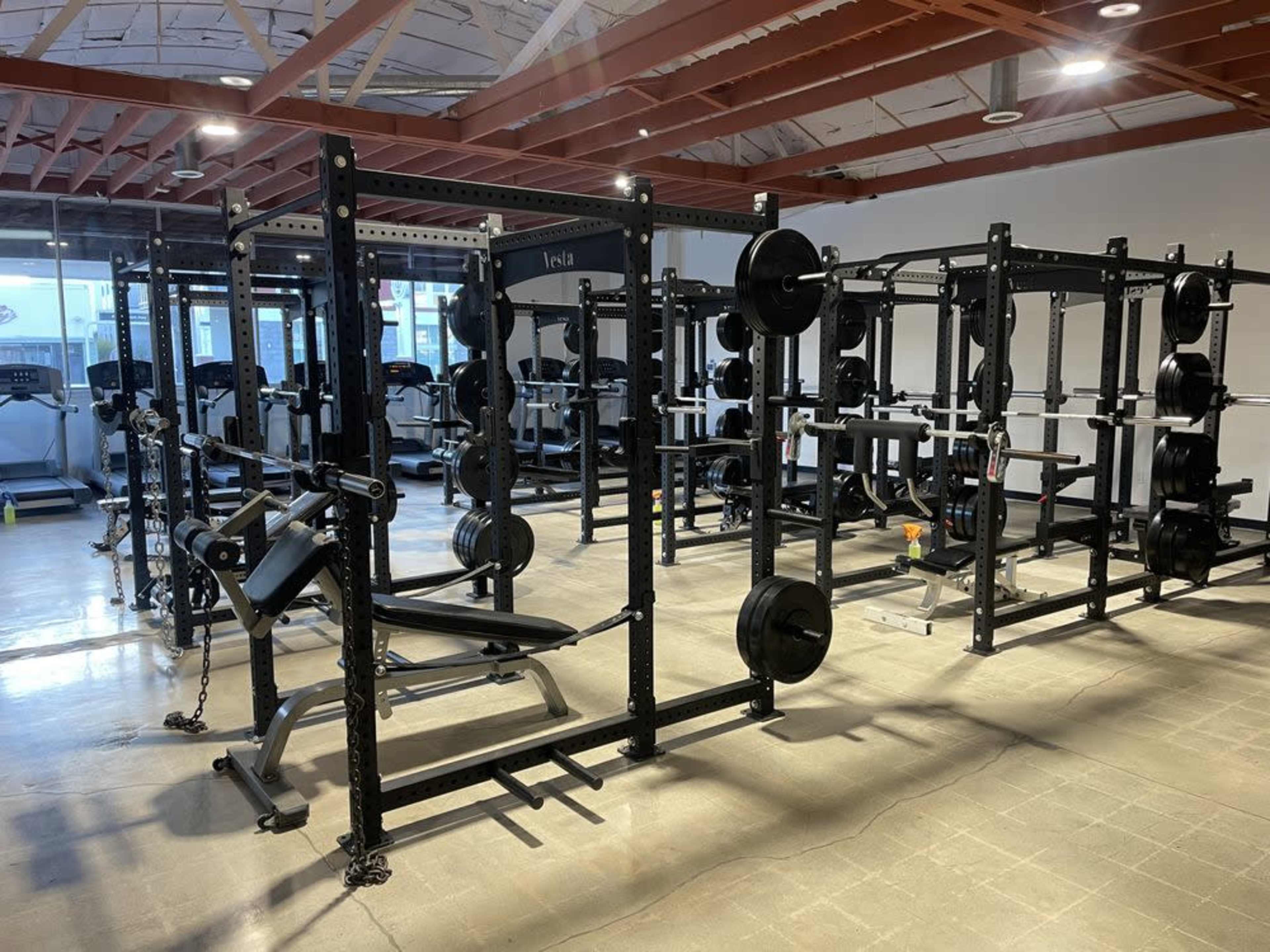 A well-equipped gym with various weightlifting machines and free weights arranged neatly.