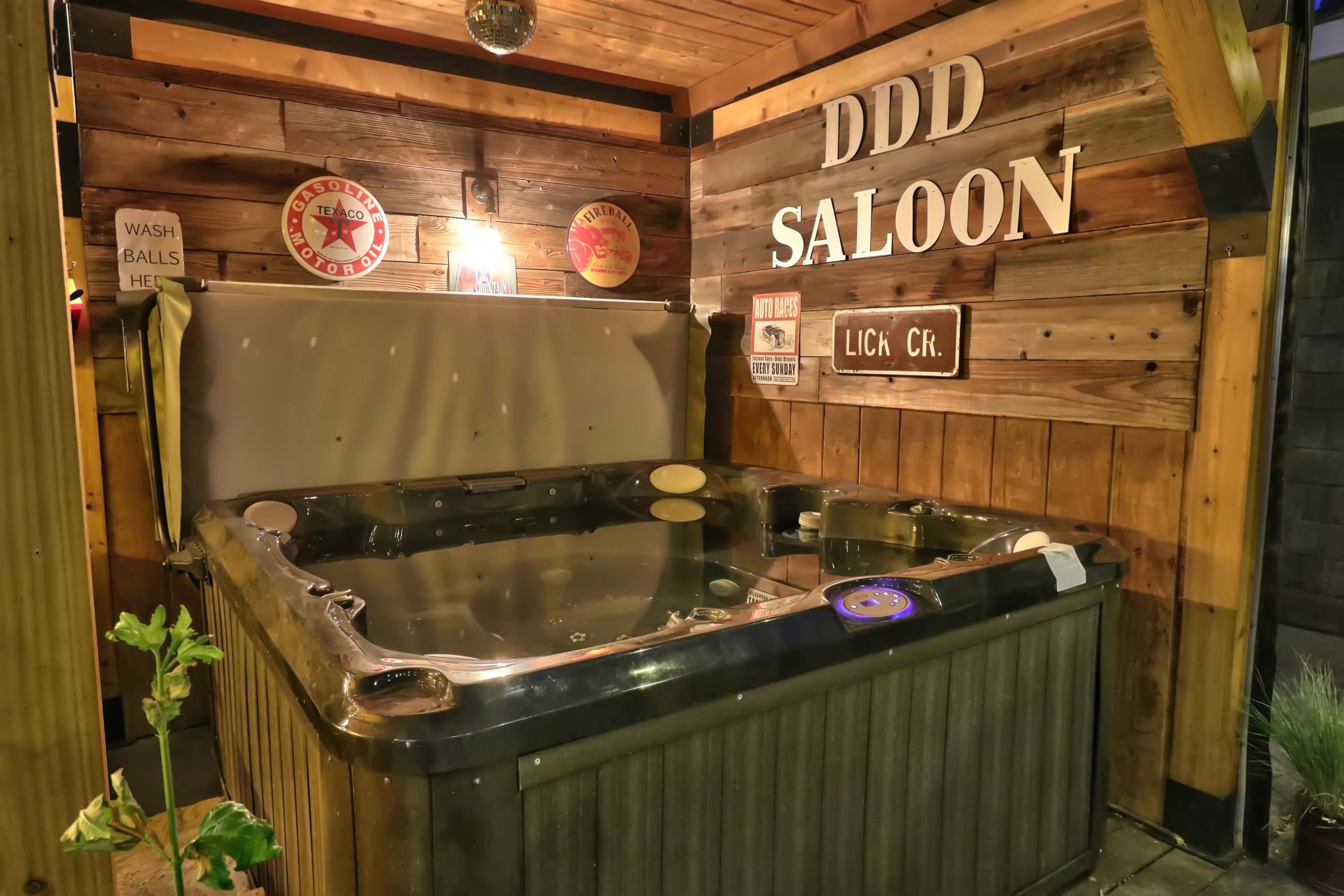 A wooden outdoor area with a hot tub positioned under a sign that reads "DDD SALOON."