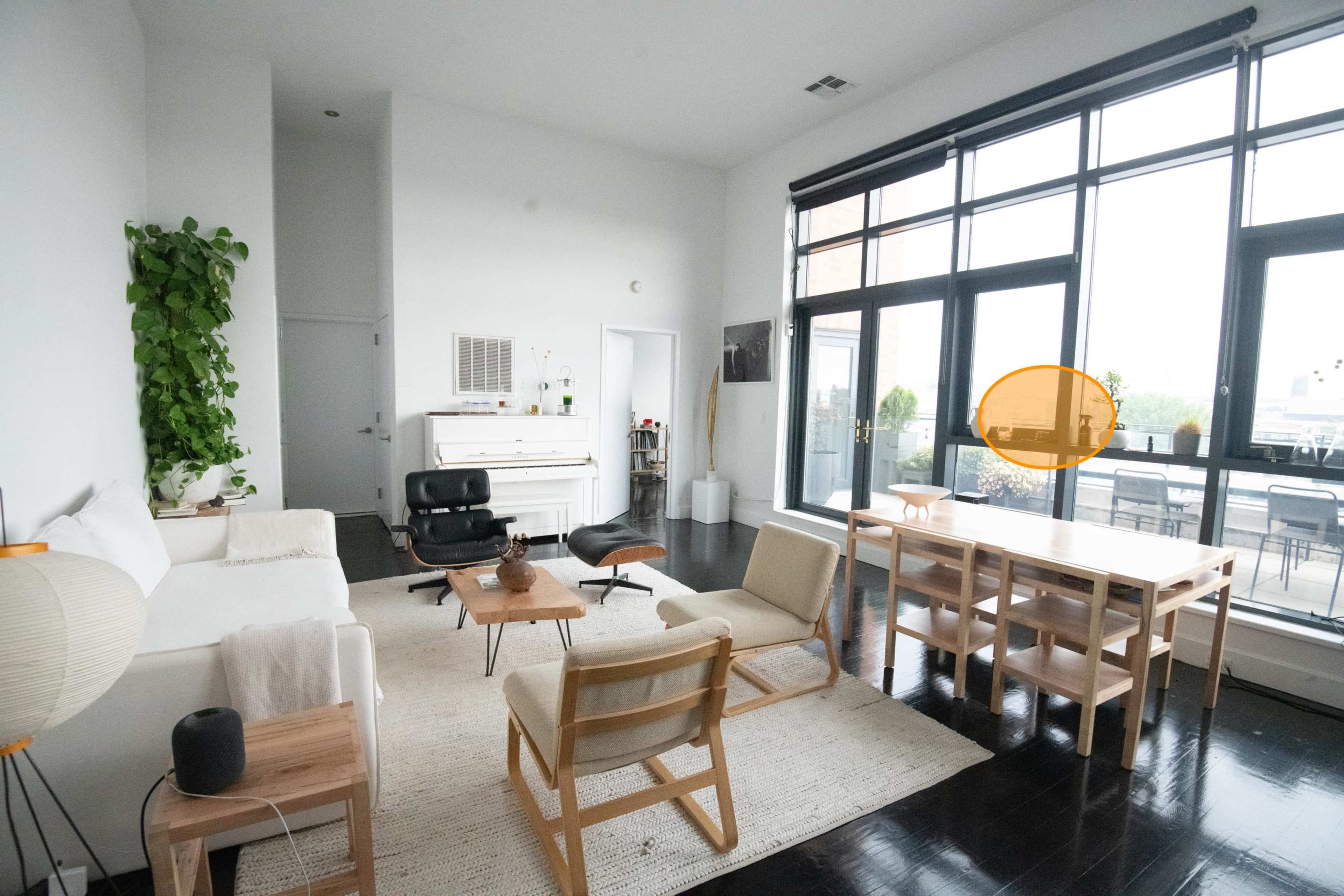 A spacious living area with a white sofa, wooden furniture, and large windows overlooking a patio.