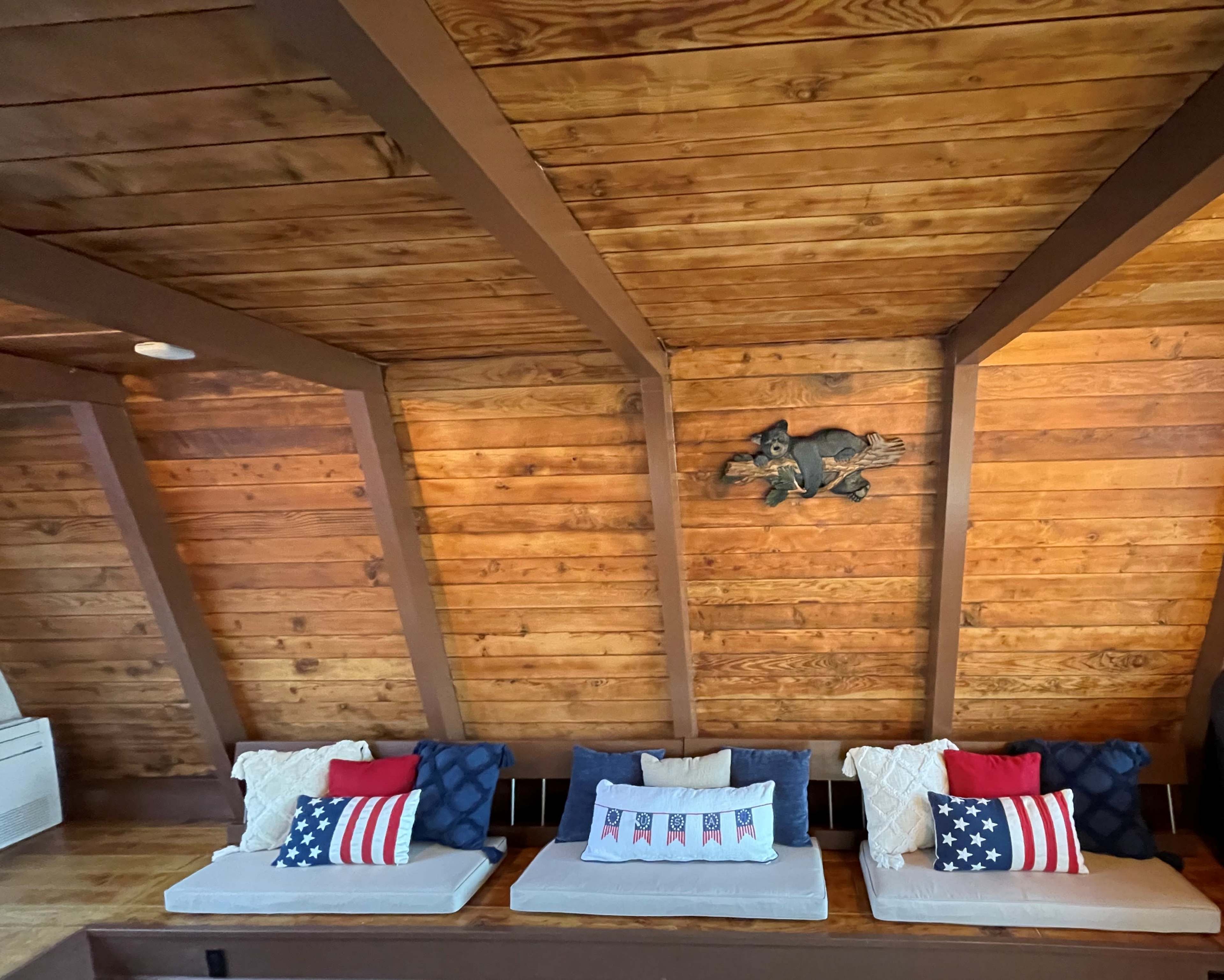 The interior features a wooden, sloped ceiling with three cushioned seats adorned with patriotic-themed pillows.