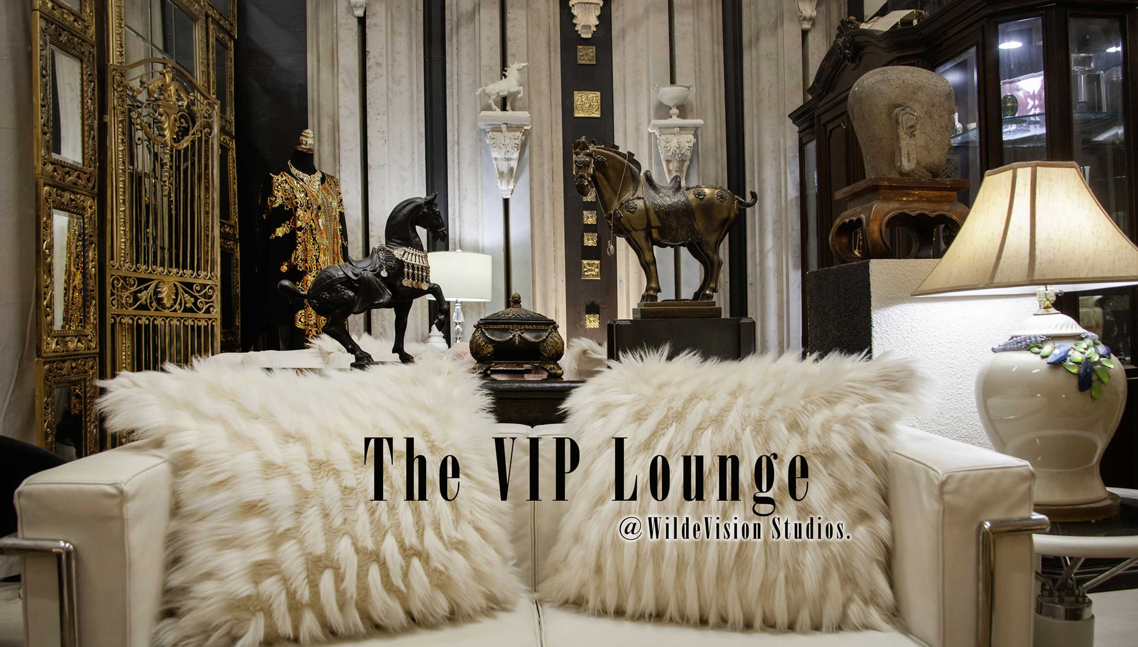 The image depicts a luxurious lounge area featuring ornate decor, including statues, decorative items, and a pair of fluffy pillows on a white sofa.