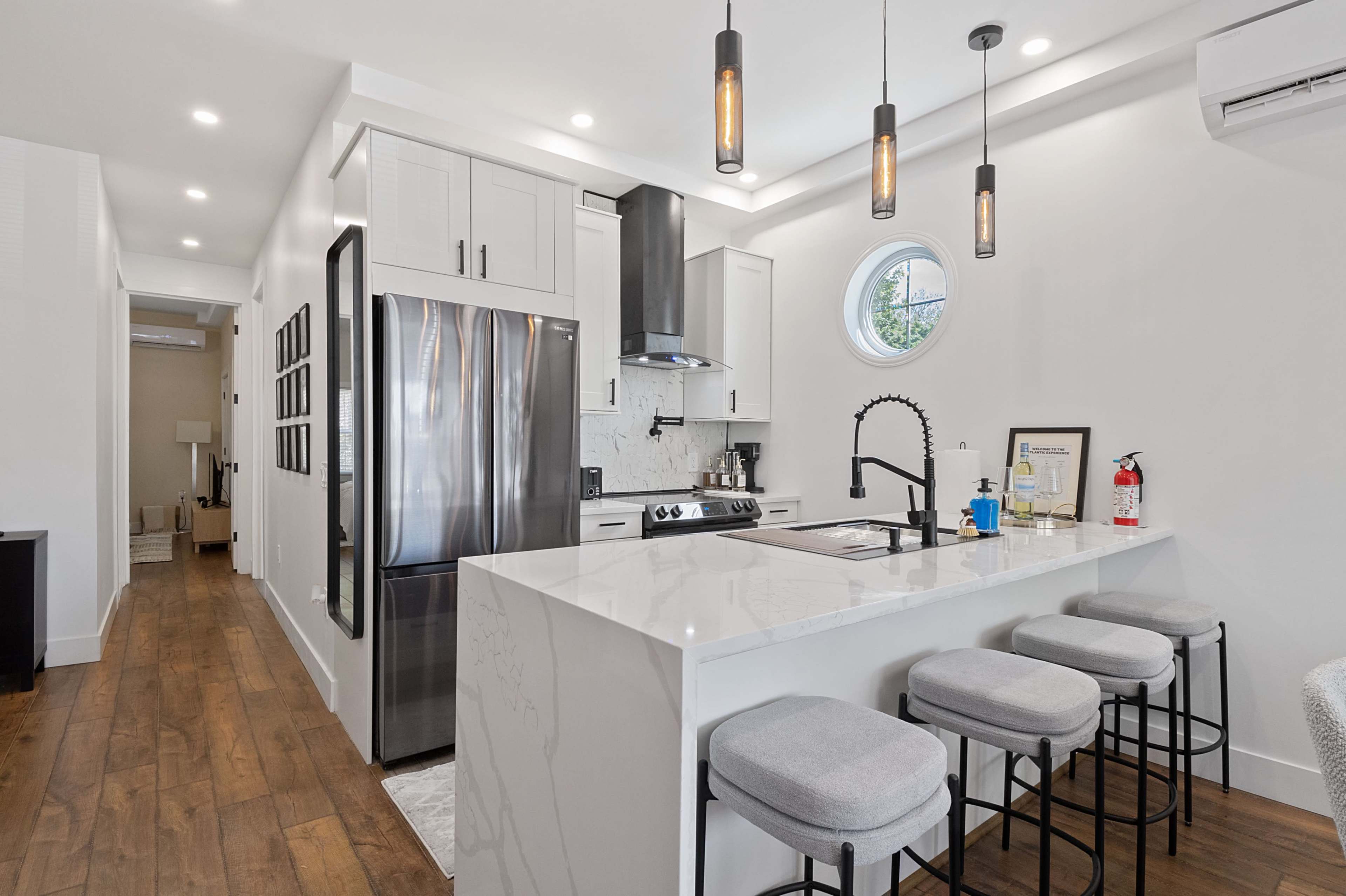 A modern kitchen featuring a stainless steel refrigerator, sleek cabinetry, and a central island with bar stools.