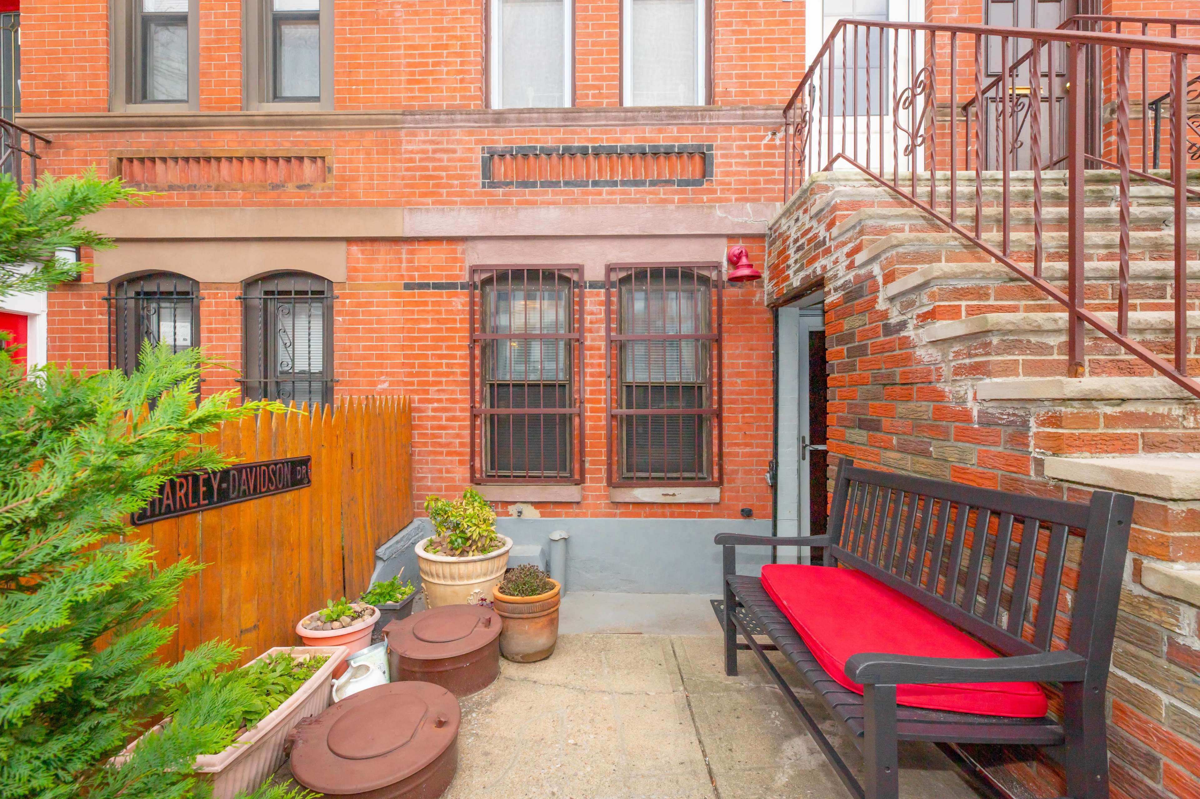 A brick courtyard with a bench, decorative planters, and a set of stairs leading to an upper level.
