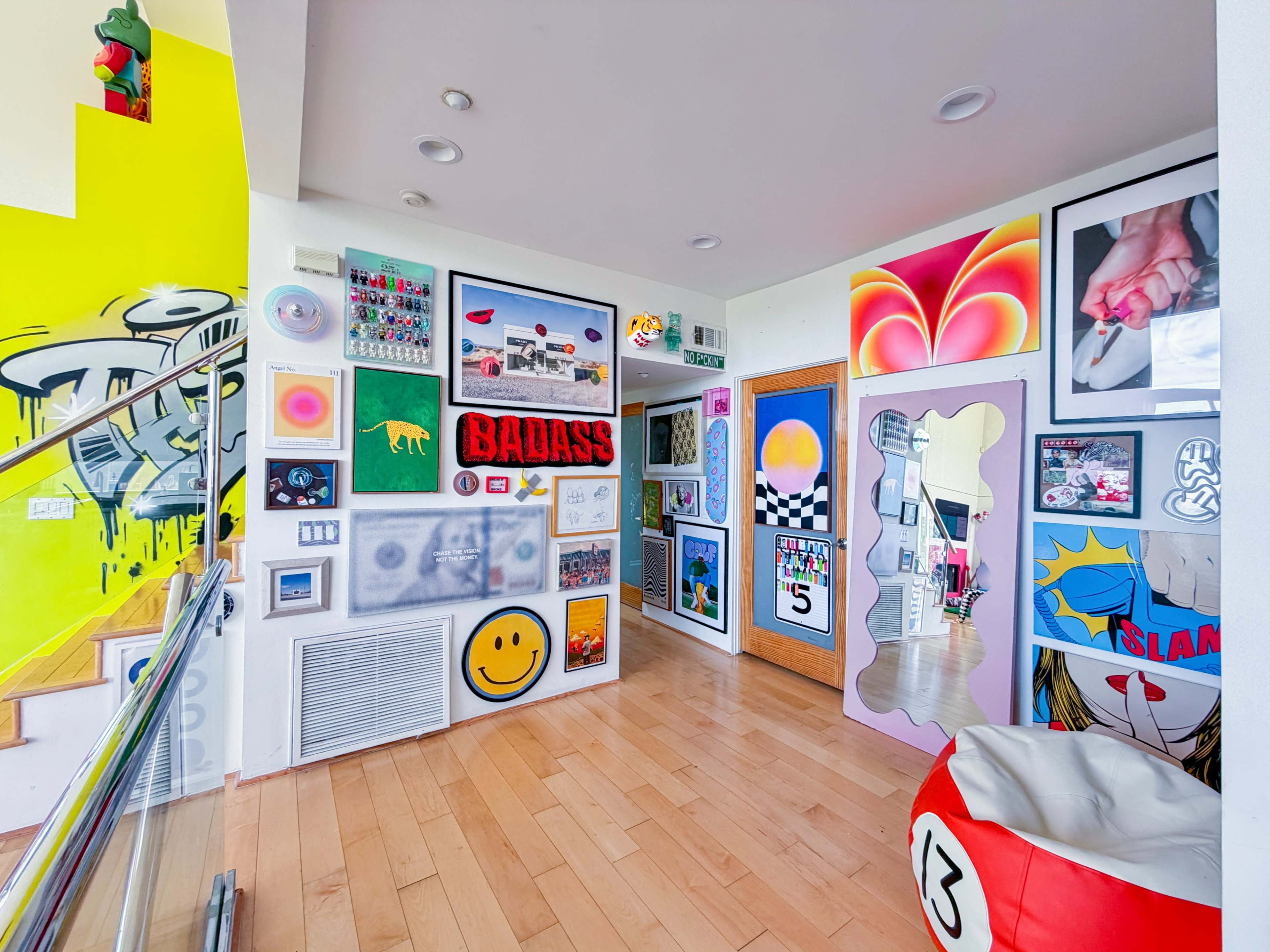 The image shows a brightly colored hallway adorned with various pieces of contemporary art and a mix of playful decor elements.