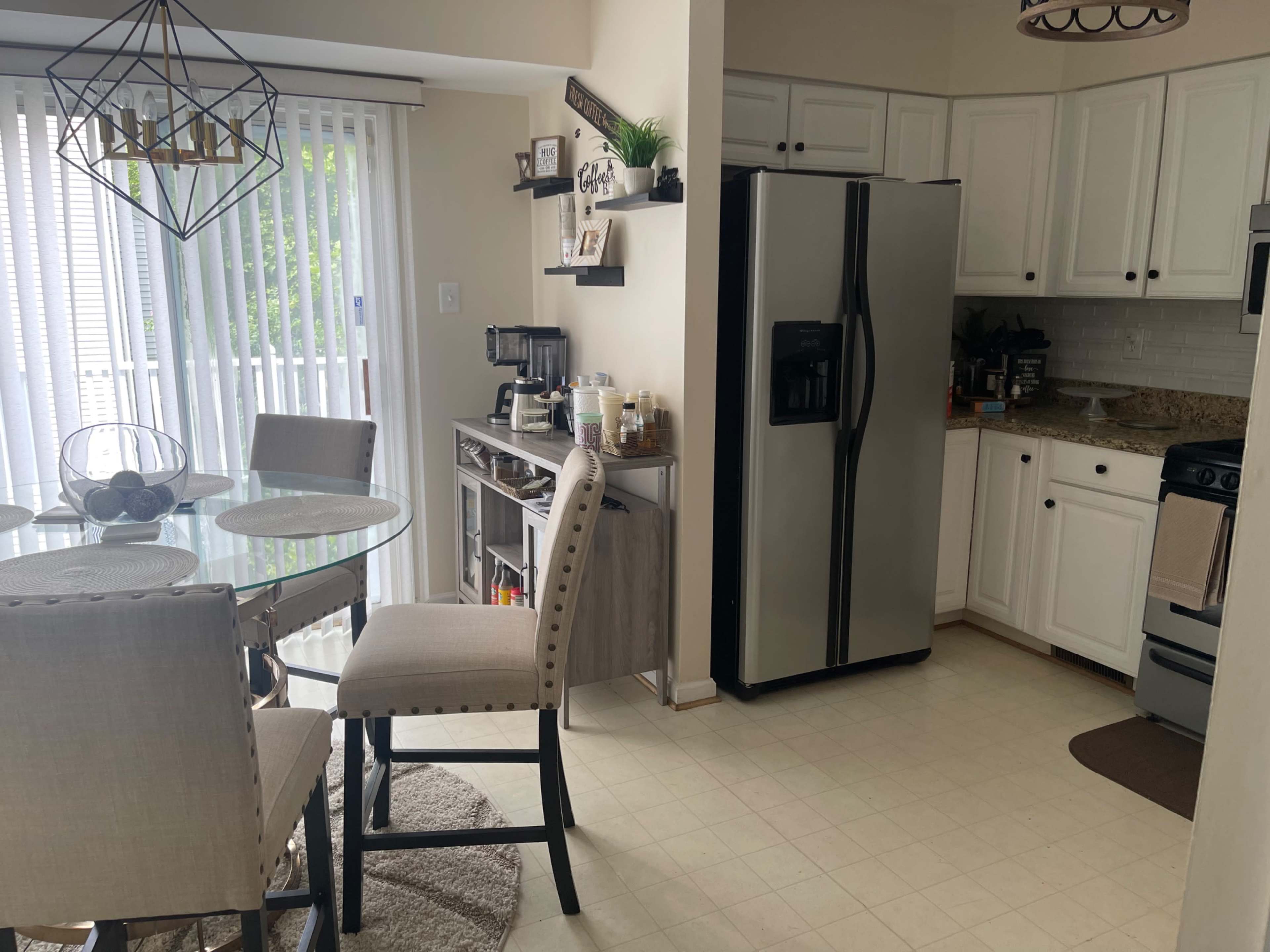 A modern kitchen with a round dining table, four upholstered chairs, and stainless steel appliances.