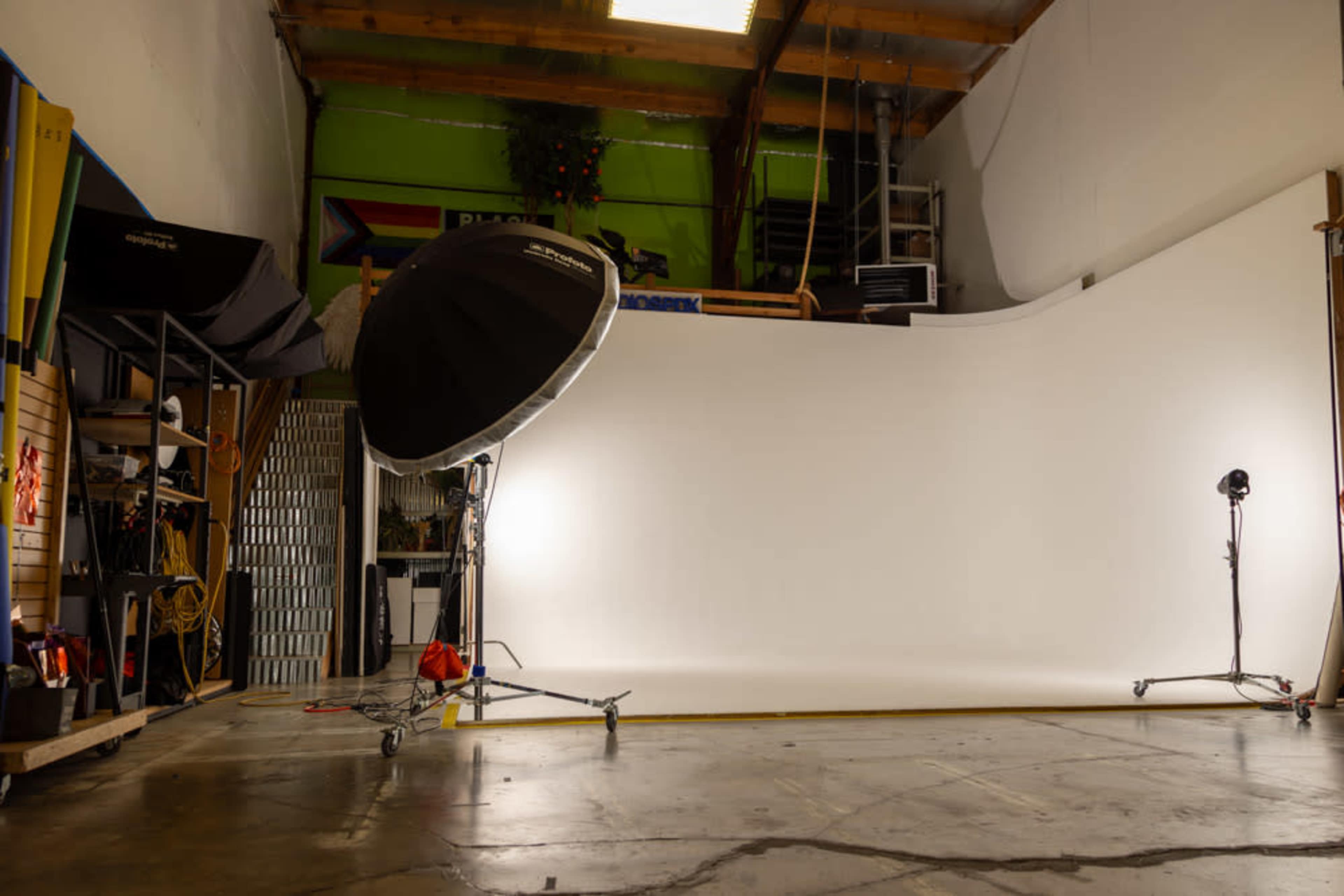 A photography studio featuring a white backdrop, lighting equipment, and various tools organized along the walls.