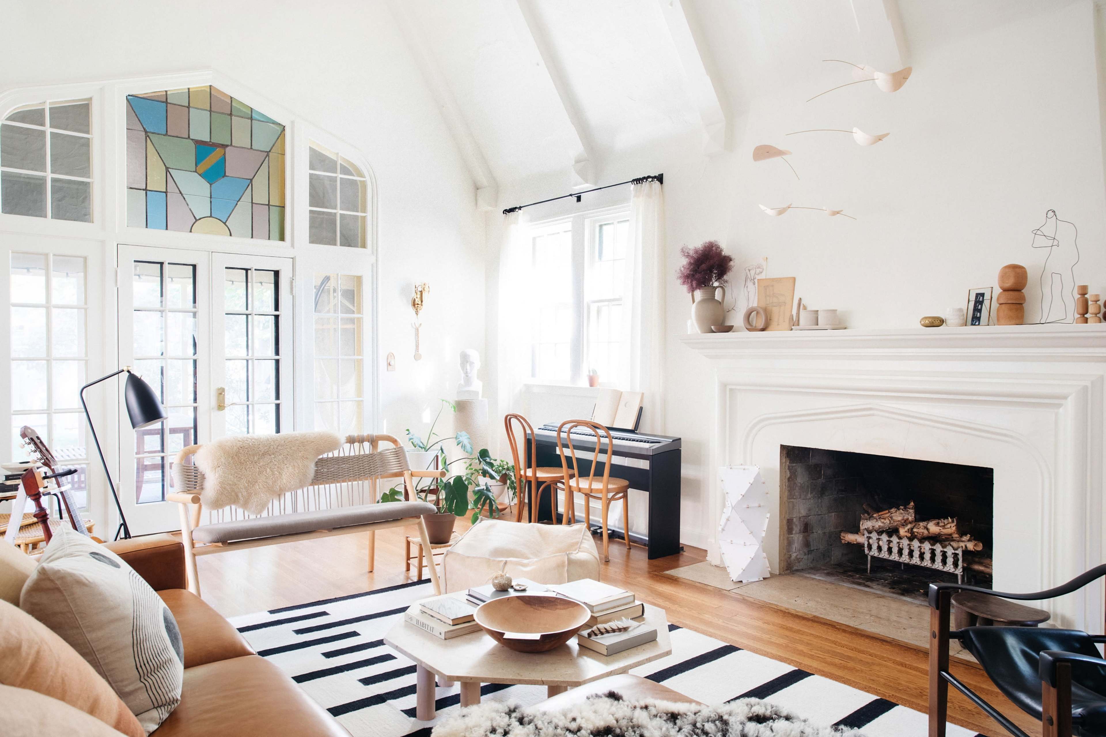 The living room features a large window with a stained glass design, a fireplace, and a mix of modern furniture and decor.