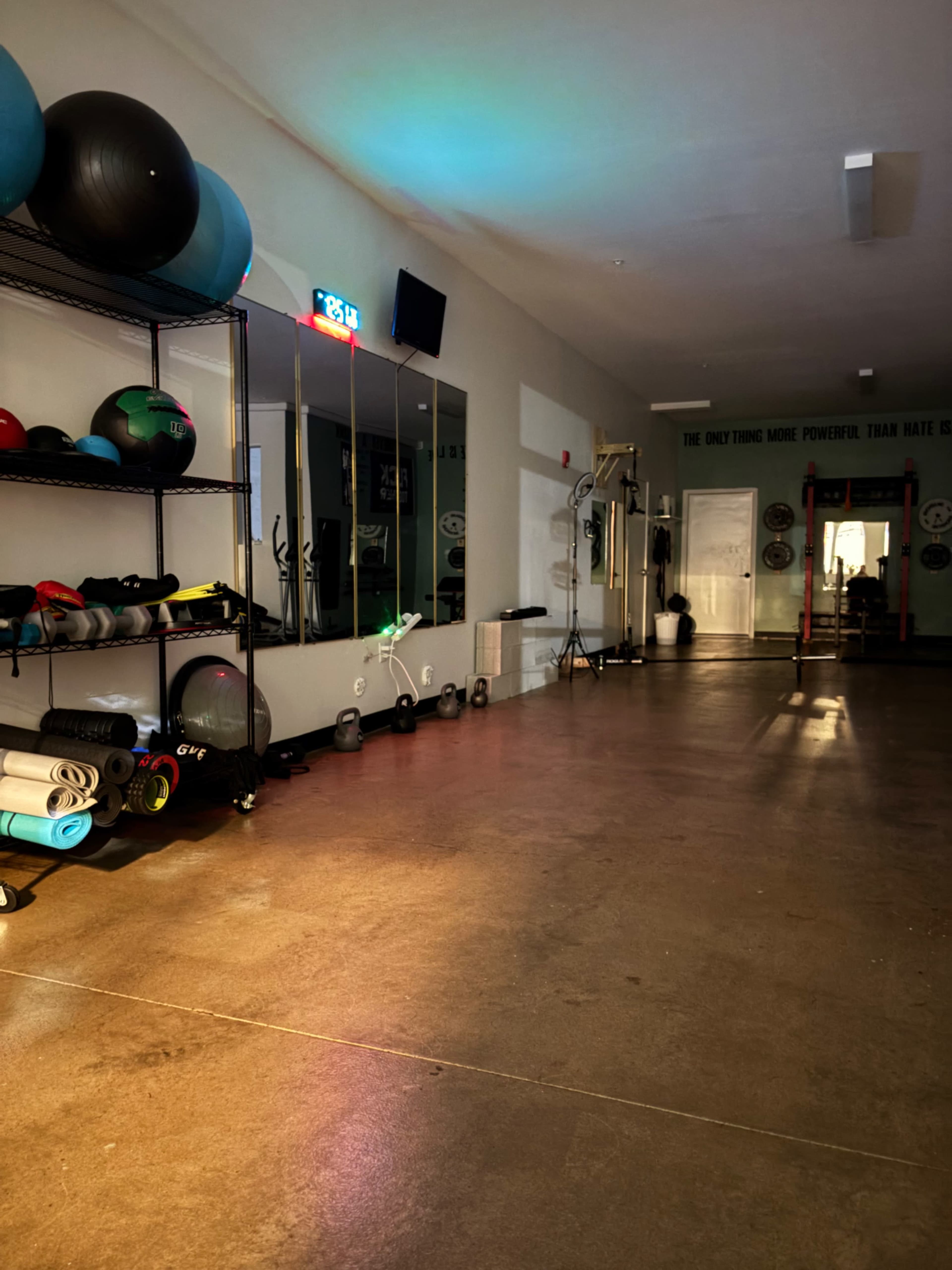 The scene shows a brightly lit fitness studio with exercise equipment arranged on shelves and mats laid out on the floor.