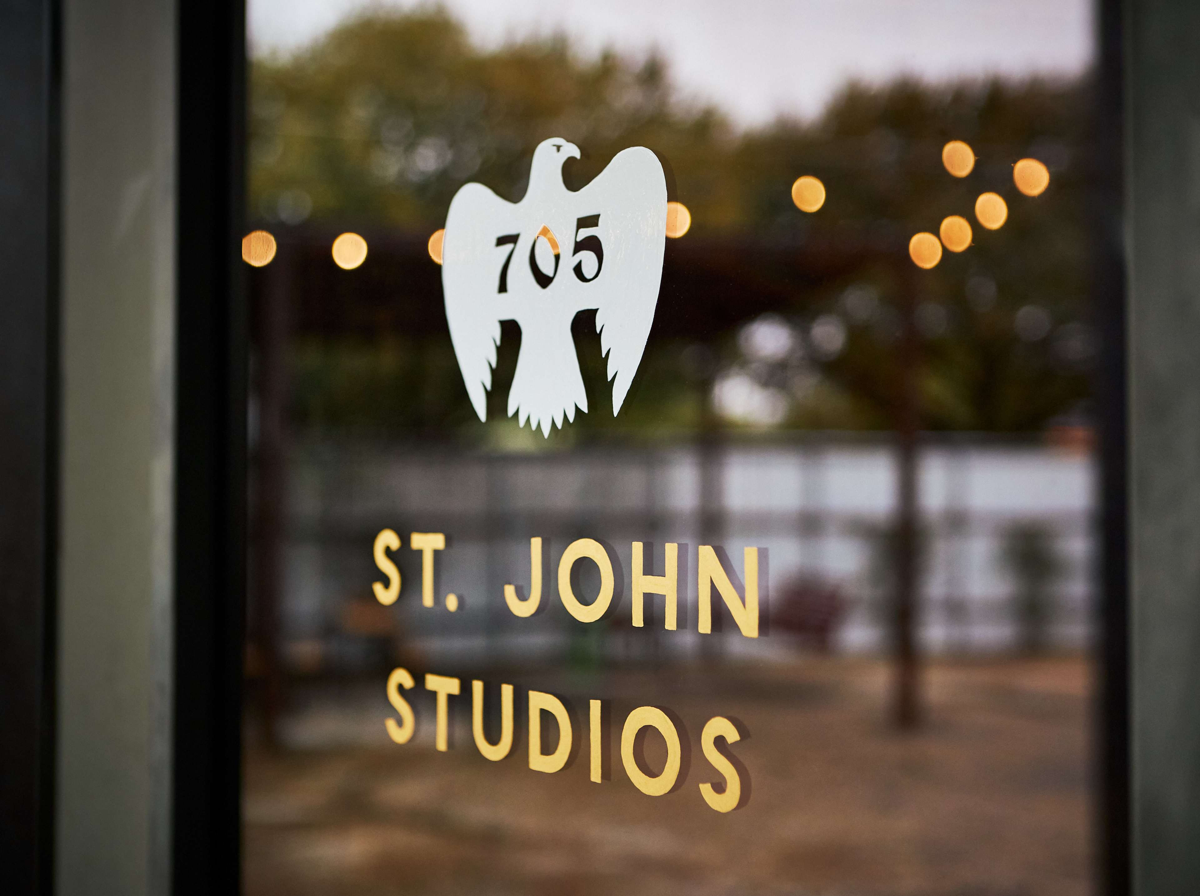 A glass door with a white eagle logo and the text "St. John Studios" in gold lettering.