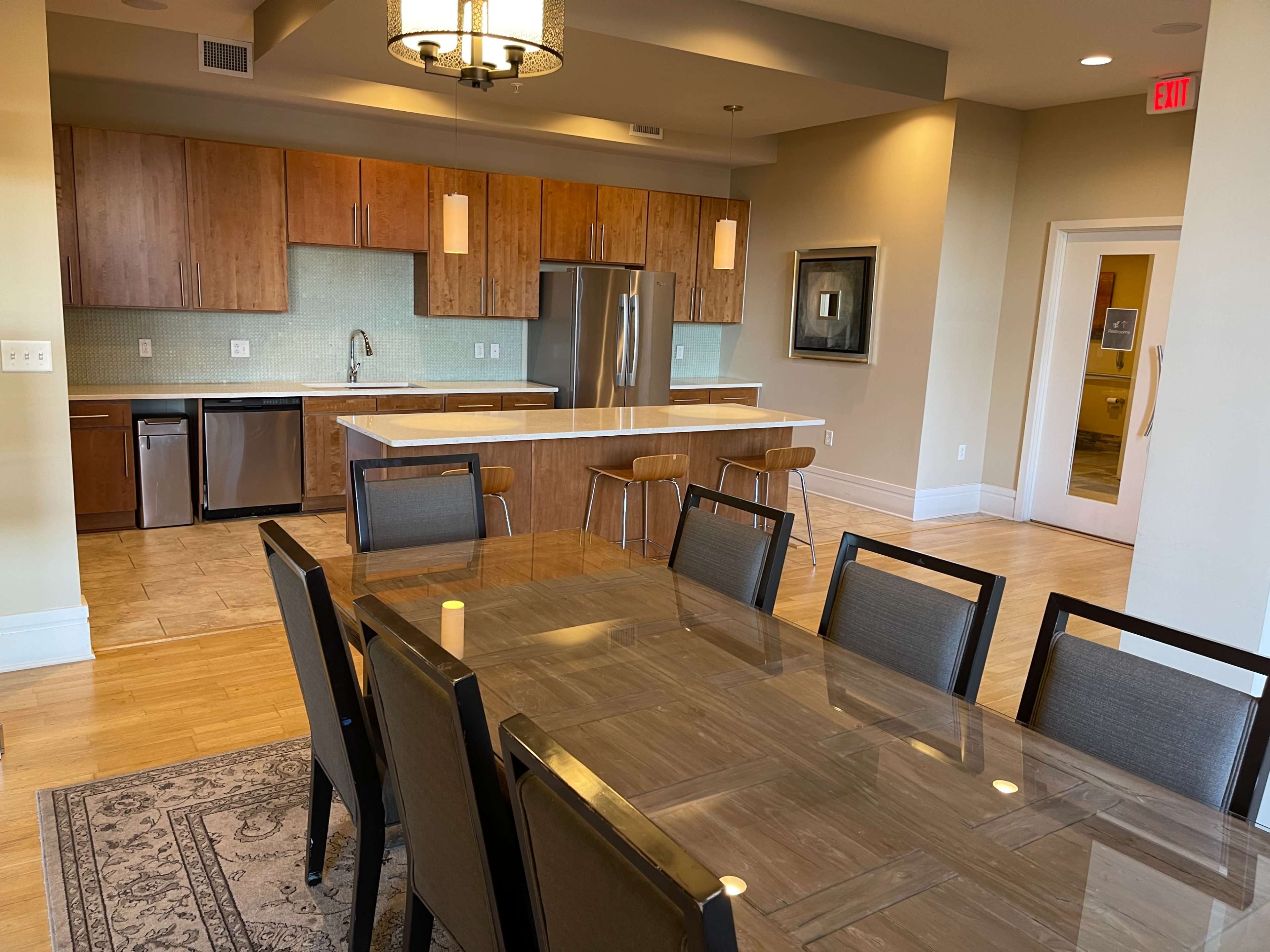 A modern kitchen and dining area featuring a large table, wooden cabinetry, and stainless steel appliances.