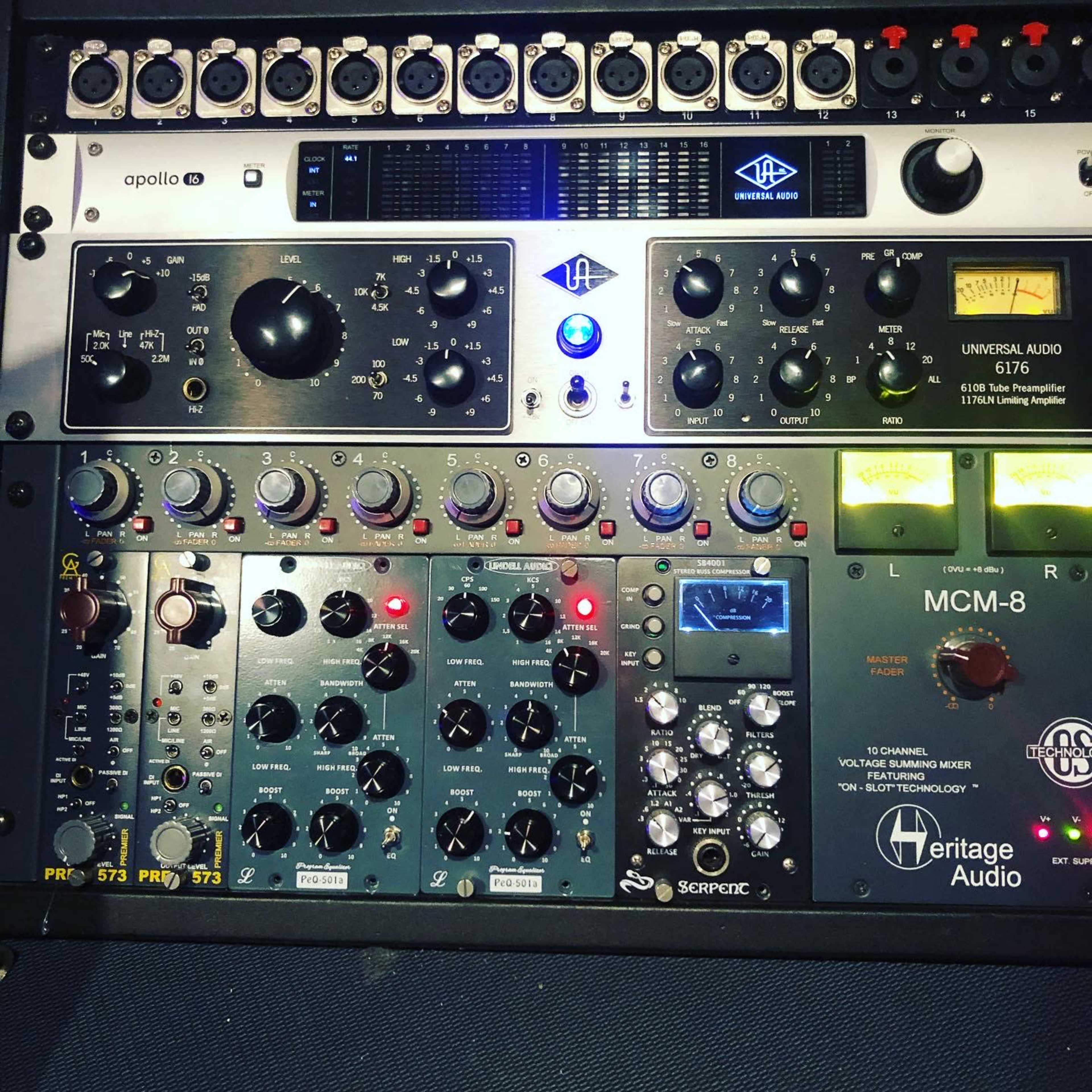 A rack of audio equipment featuring several processors, including a Universal Audio interface and Heritage Audio modules.
