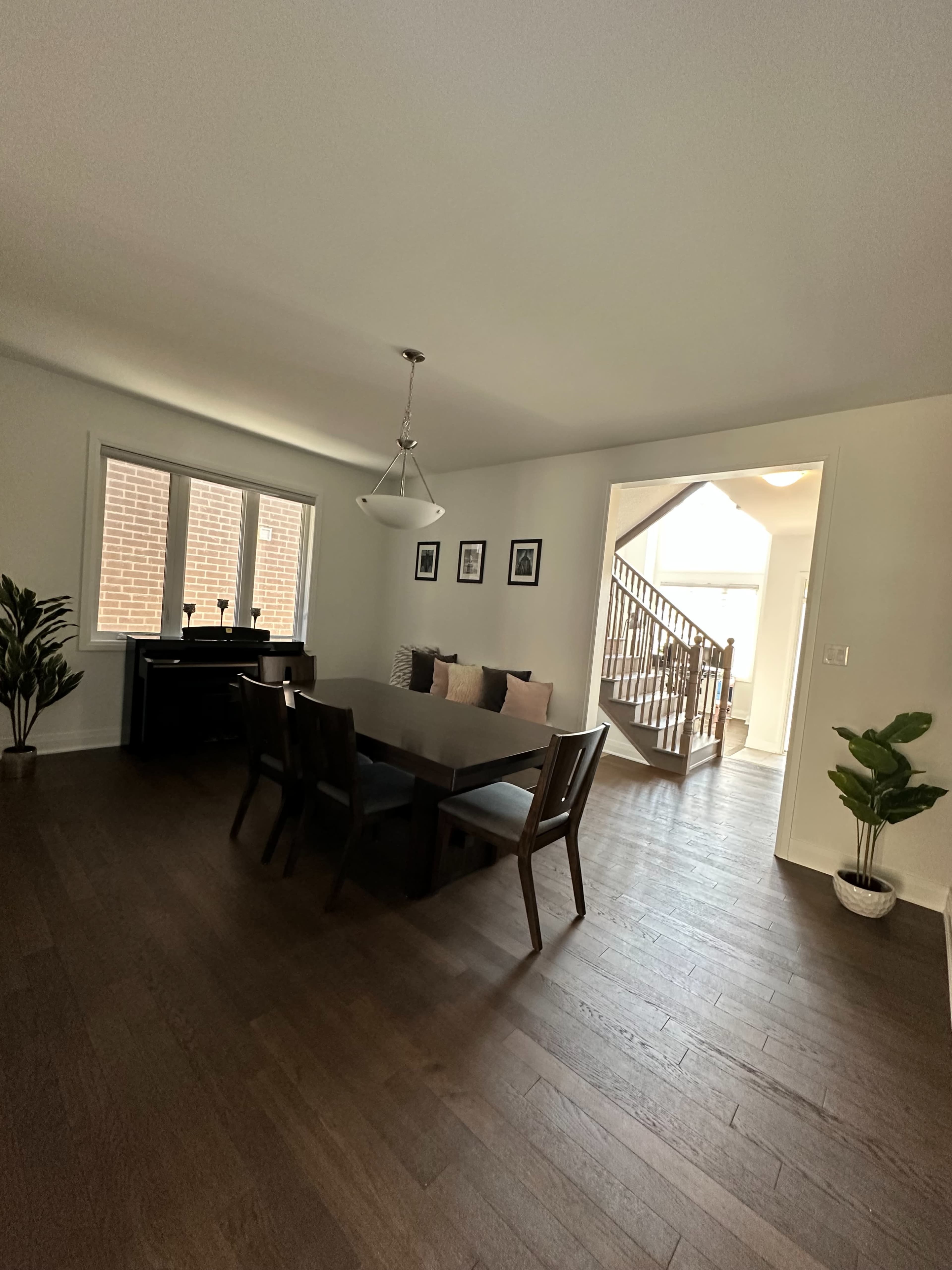 A dining area with a rectangular table surrounded by chairs, and a staircase leading to another level in the background.