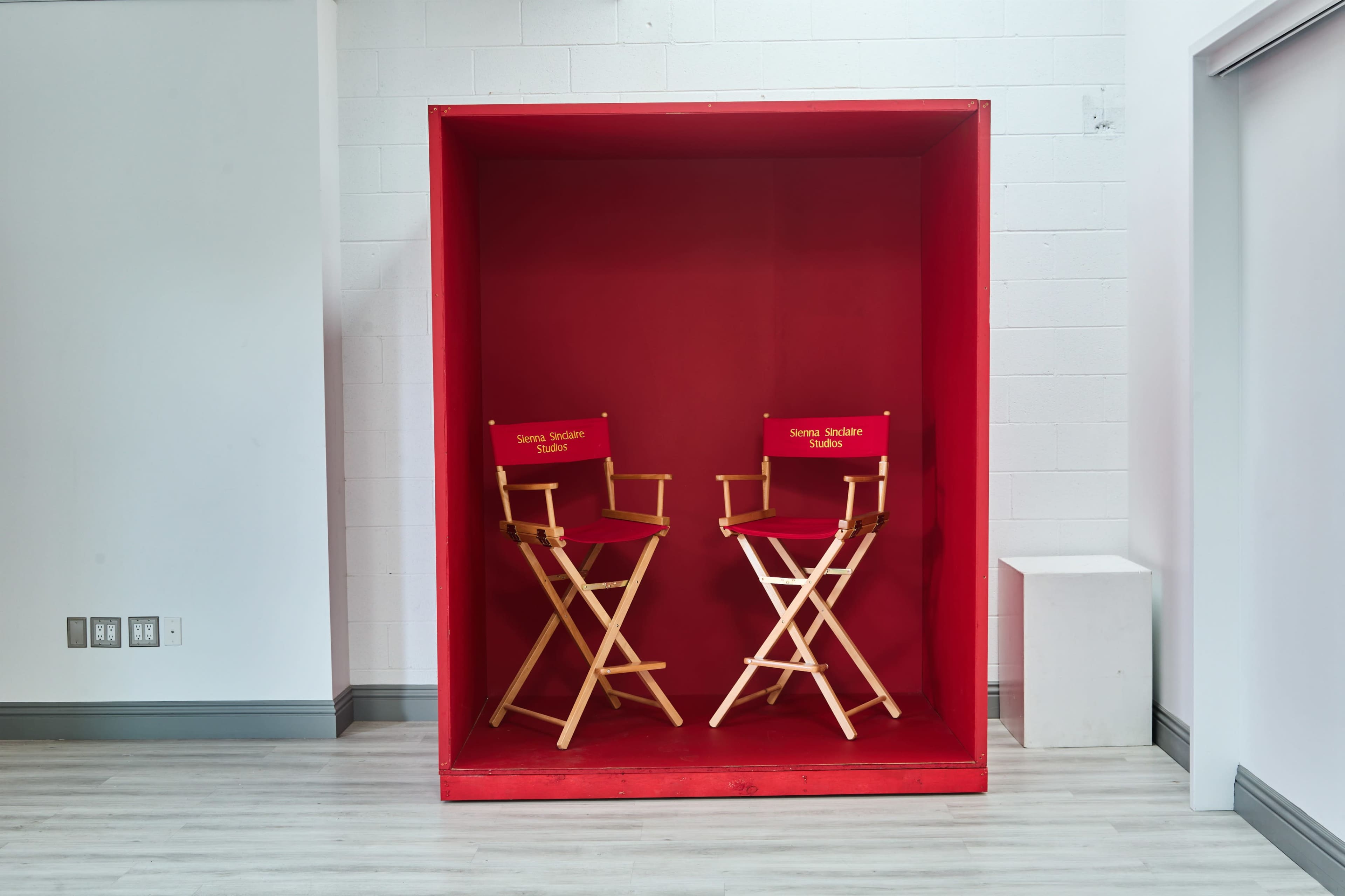 A large red box contains two wooden director's chairs with gold lettering inside.