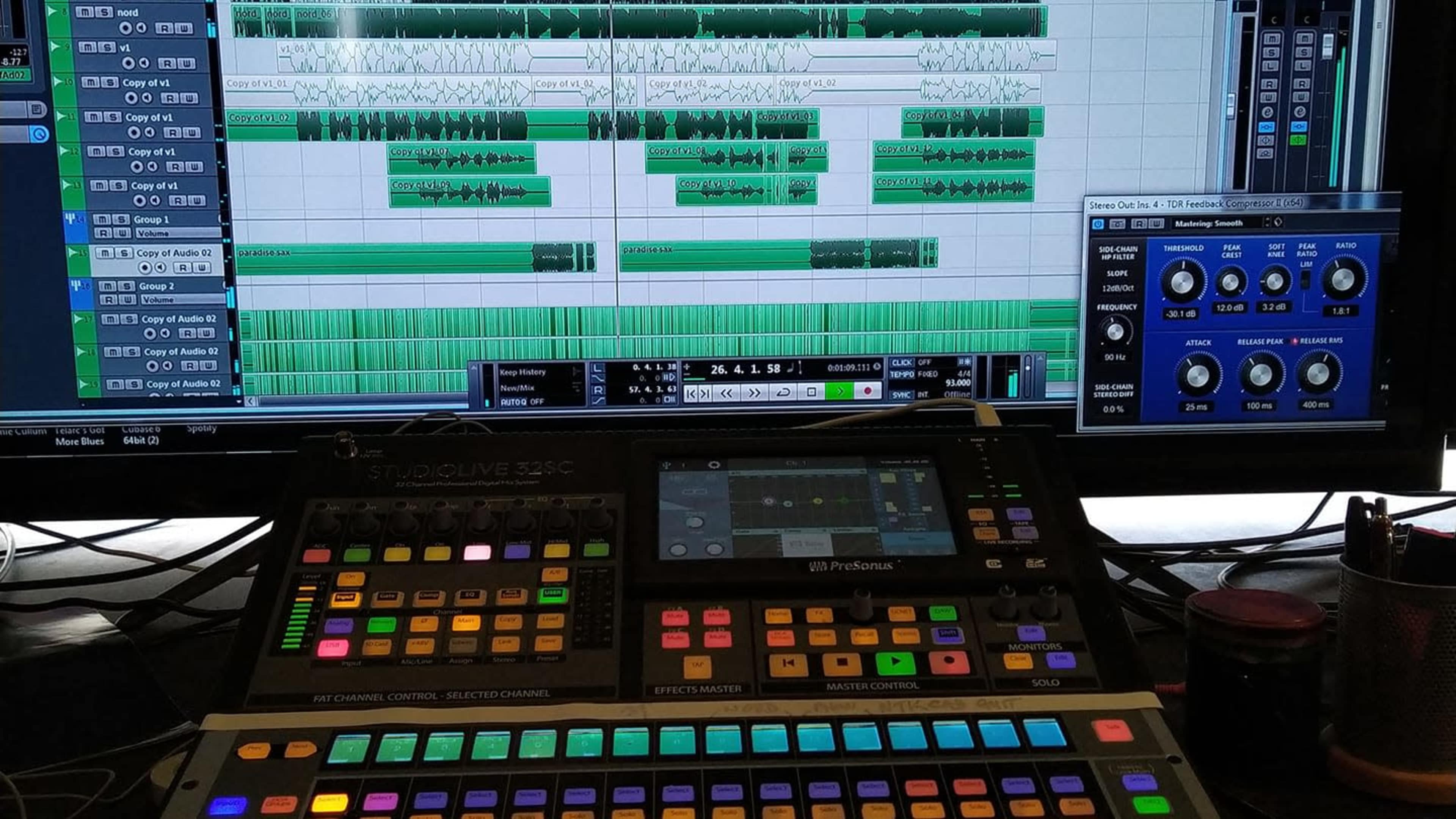 A digital audio workstation displays a music production interface with multiple tracks and audio waveforms, while a control surface with colorful buttons and sliders is positioned in the foreground.