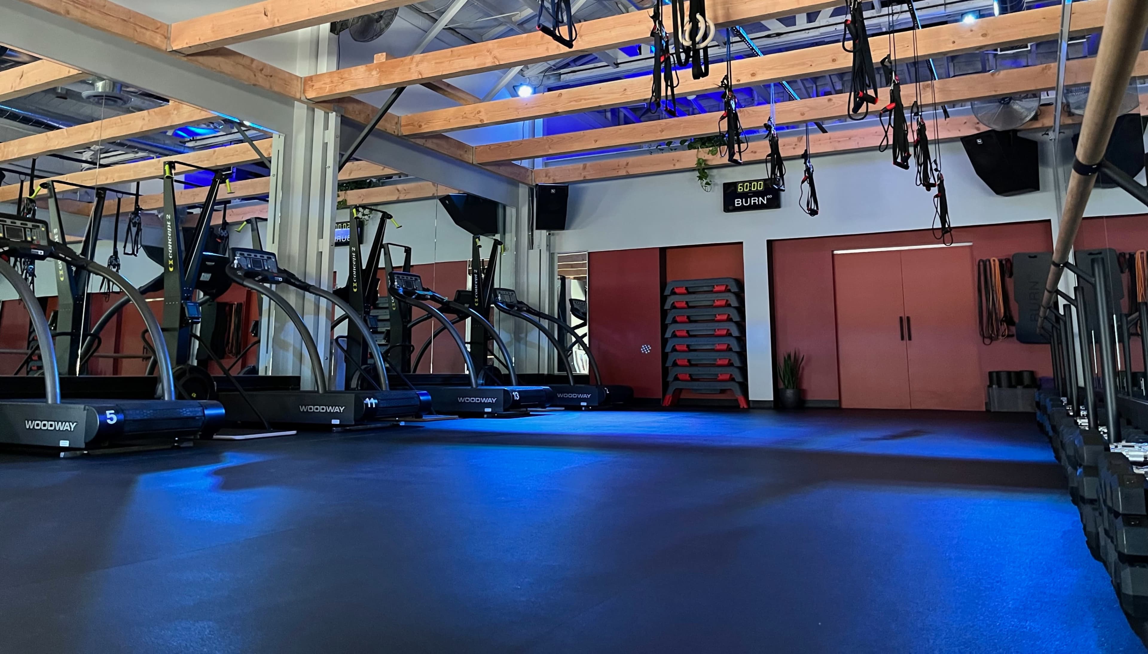 A fitness studio with various cardio machines, exercise bands, and a spacious, well-lit interior.