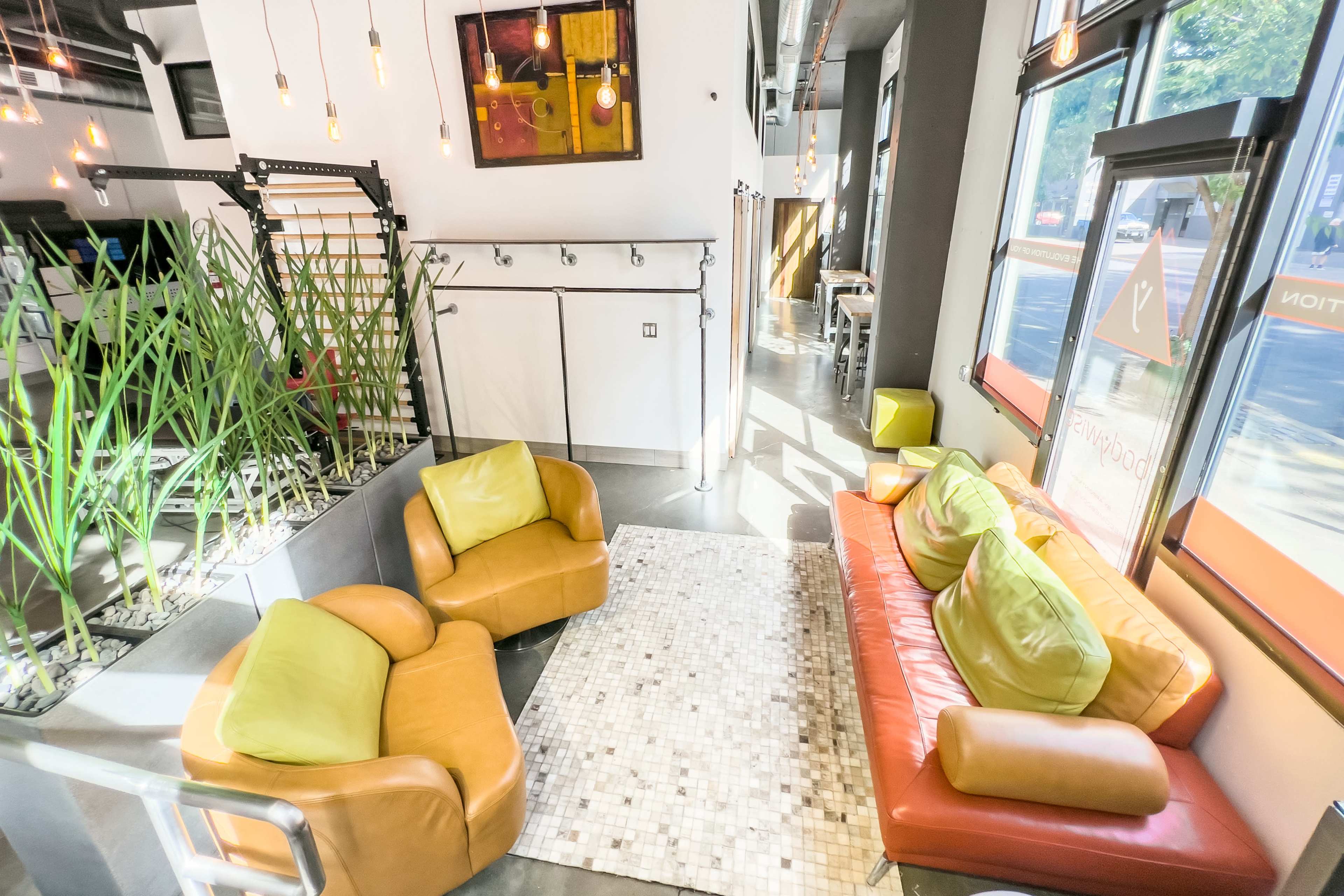 A modern seating area featuring two armchairs and a sofa, surrounded by indoor plants and large windows with natural light.