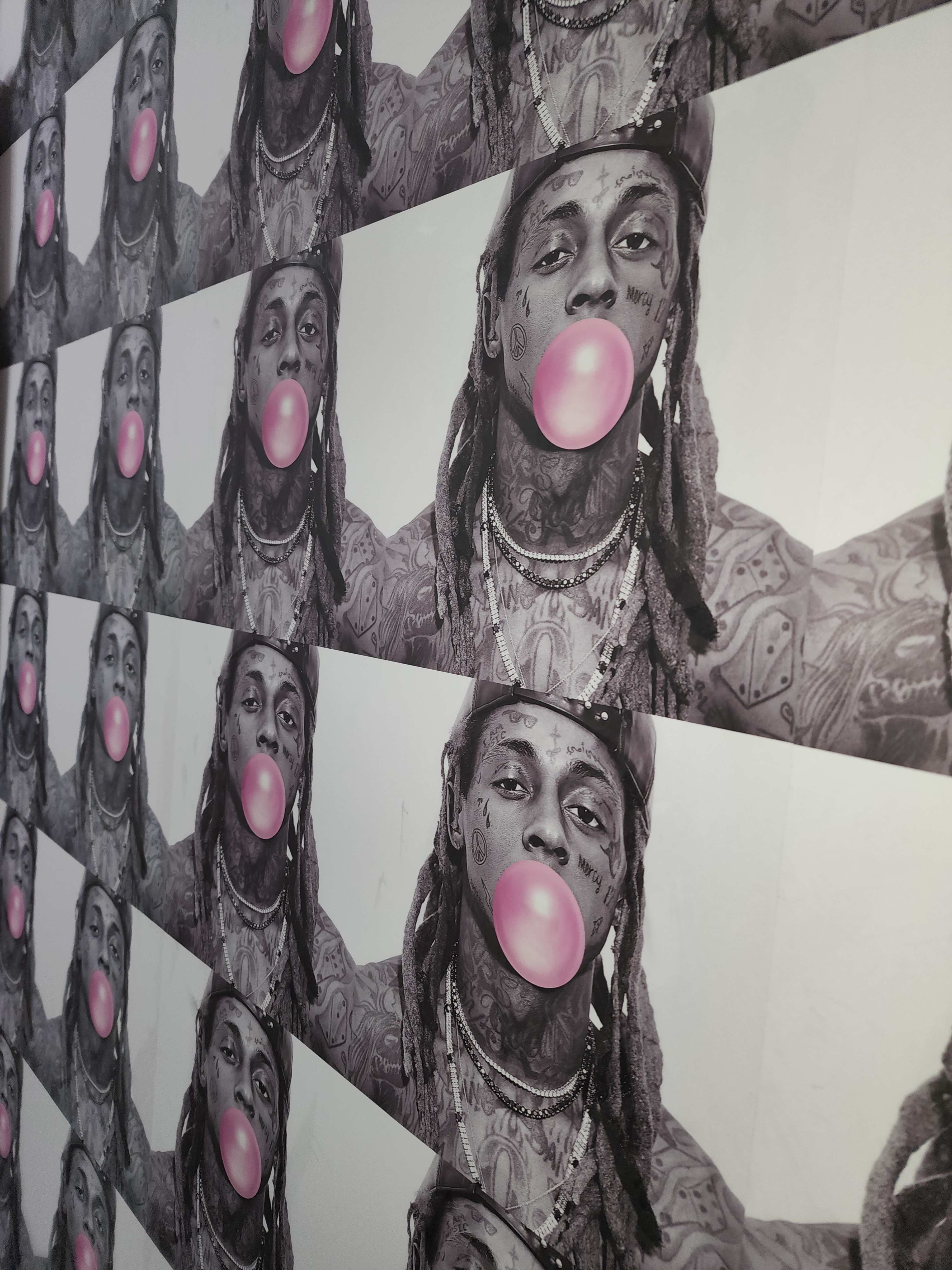 A repeated pattern of a black-and-white photograph of a person blowing a pink bubblegum bubble.