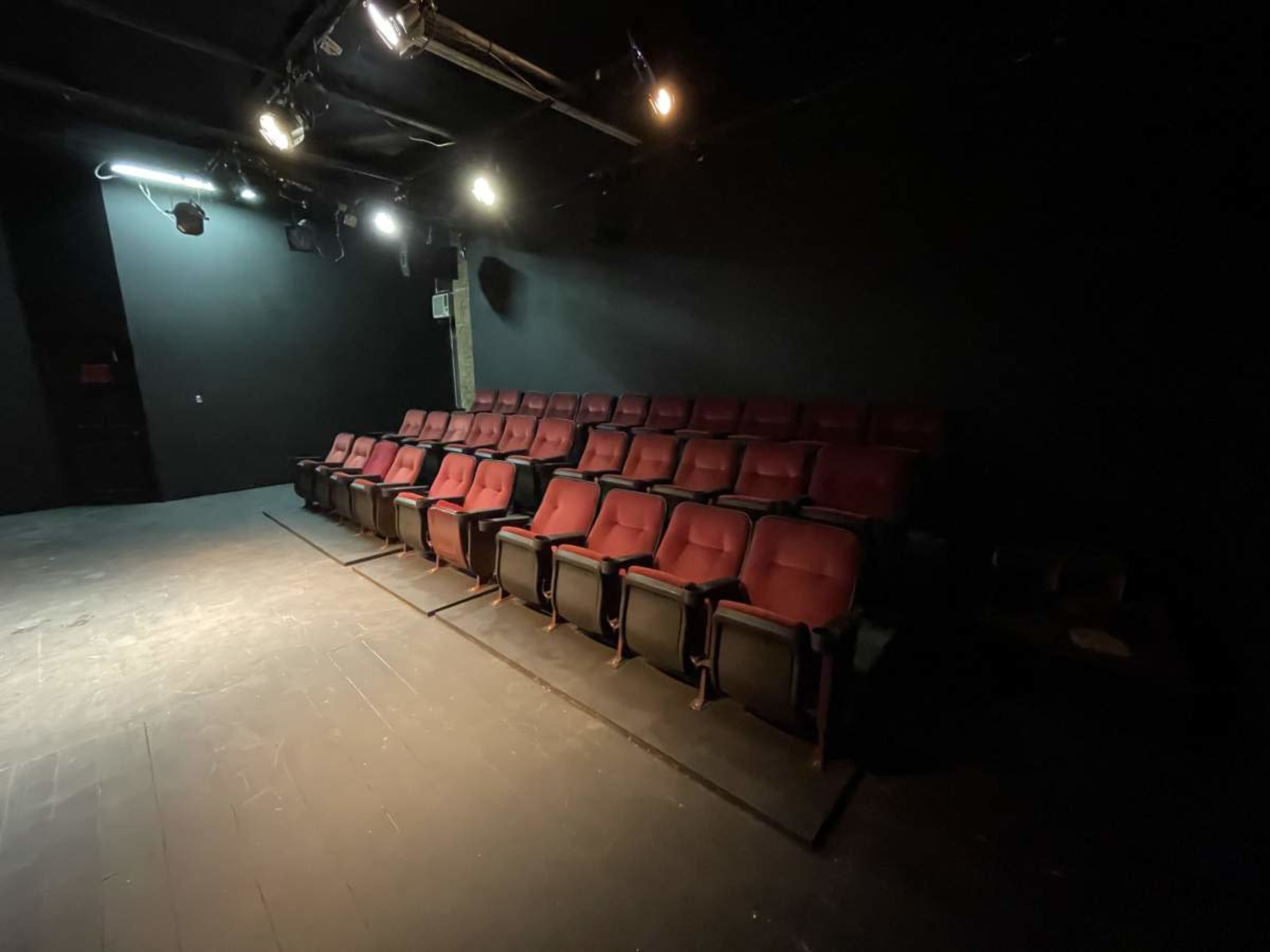 A row of red theater seats arranged in a darkened auditorium.