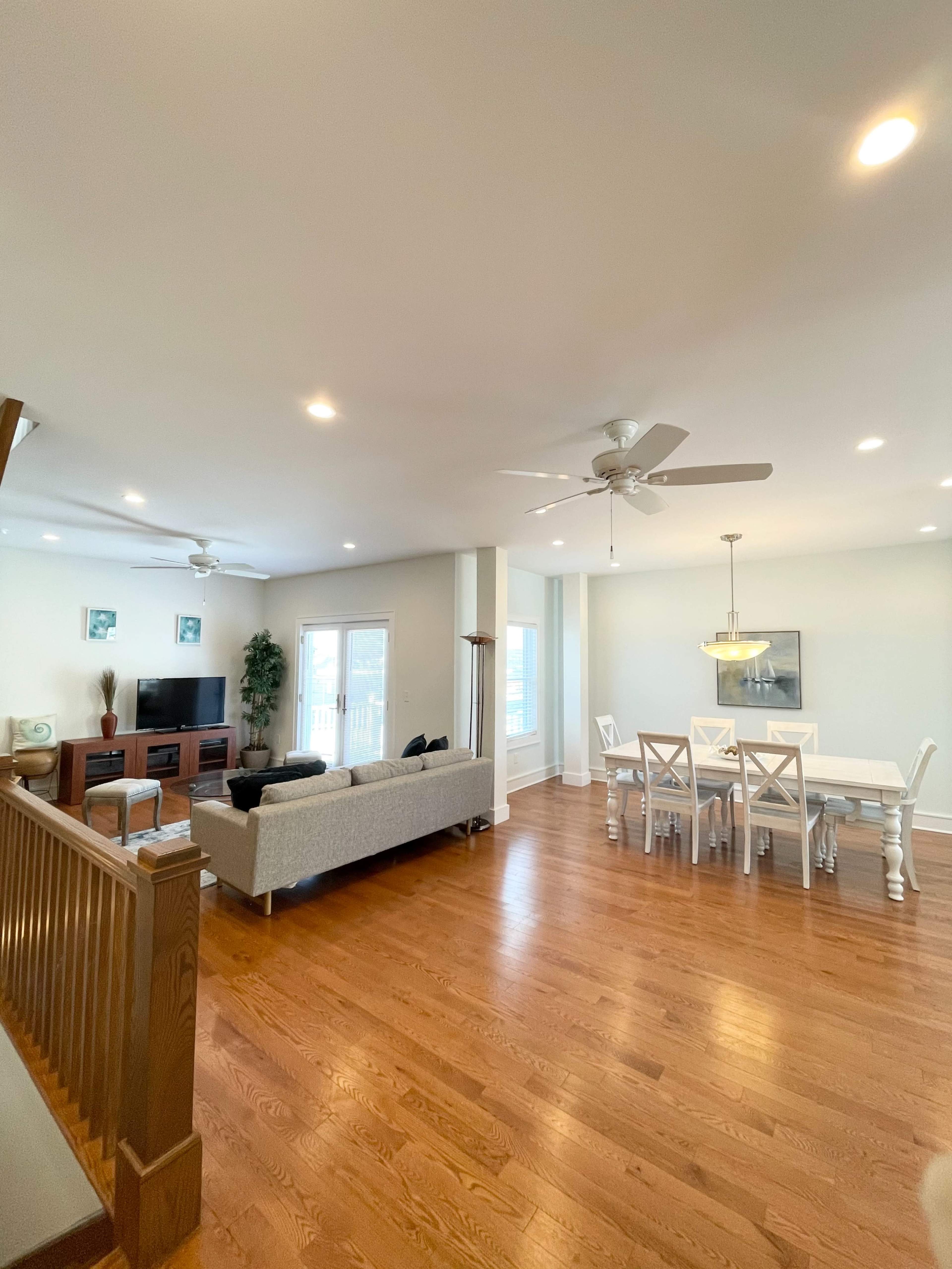 The room features an open layout with a living area containing a sofa and television, and a dining area with a table and chairs.