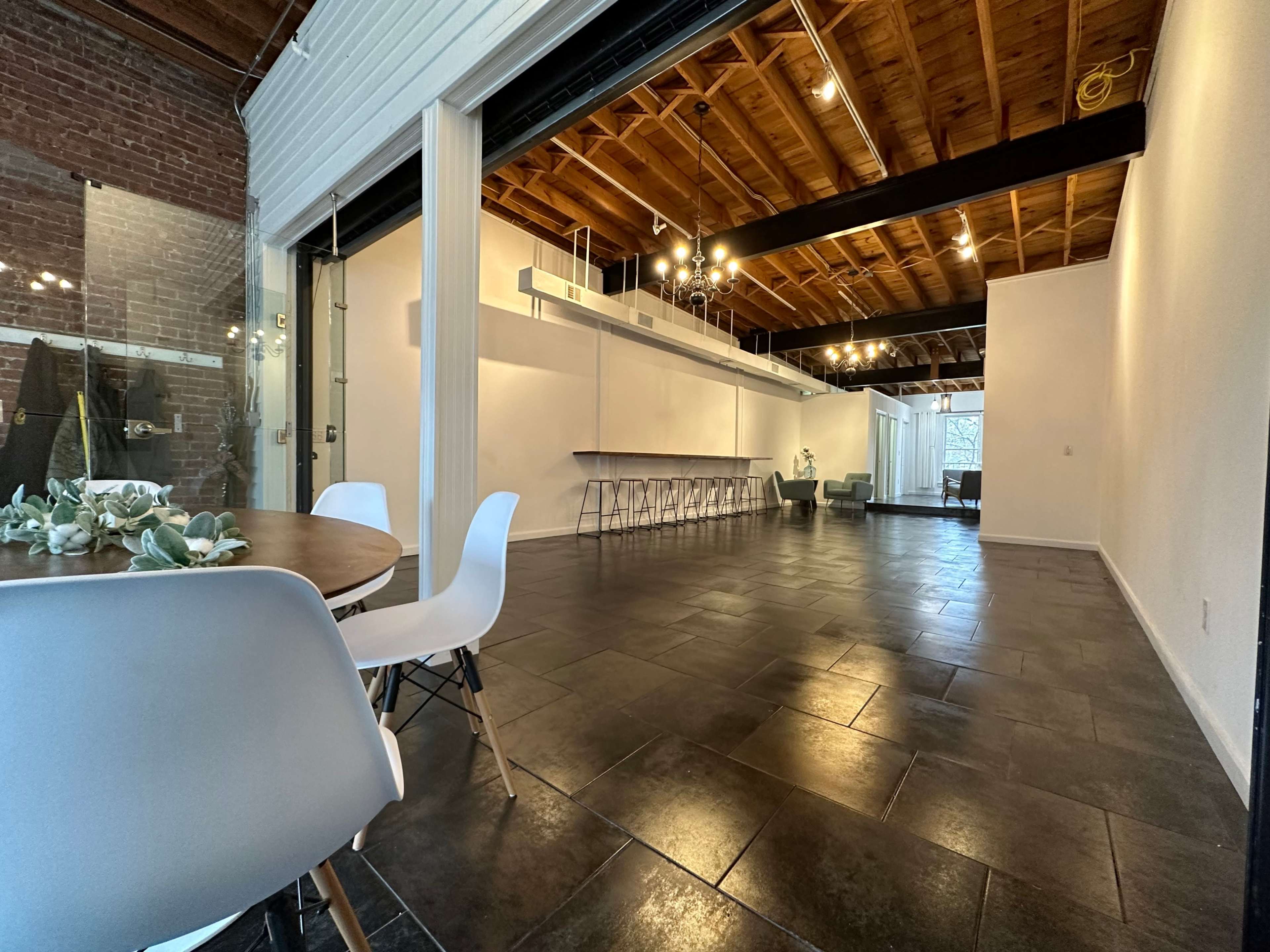 A spacious interior with a dining area featuring a round table and chairs, and an open area with a bar-like counter and multiple seating options.