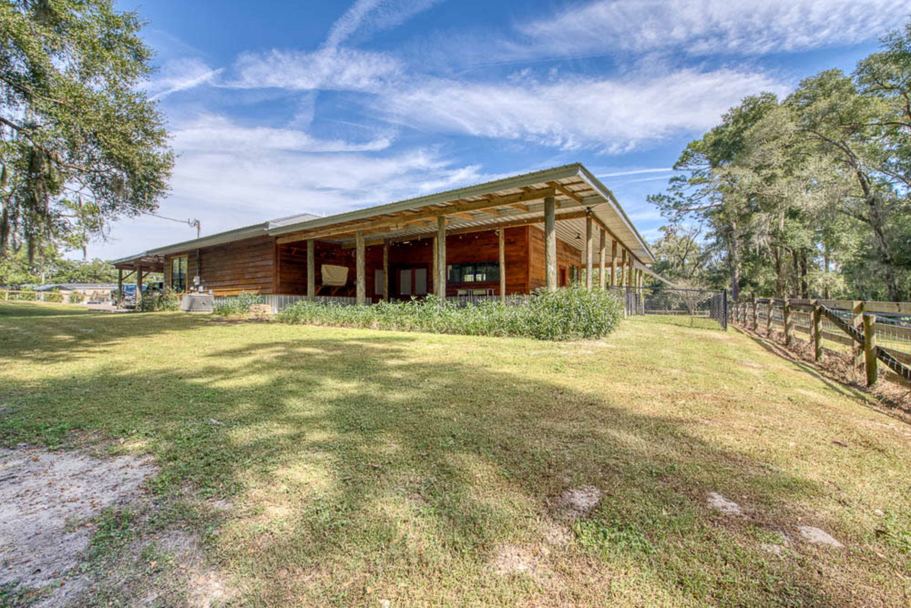 A sturdy wooden building is set on a grassy lawn surrounded by trees and a fence.