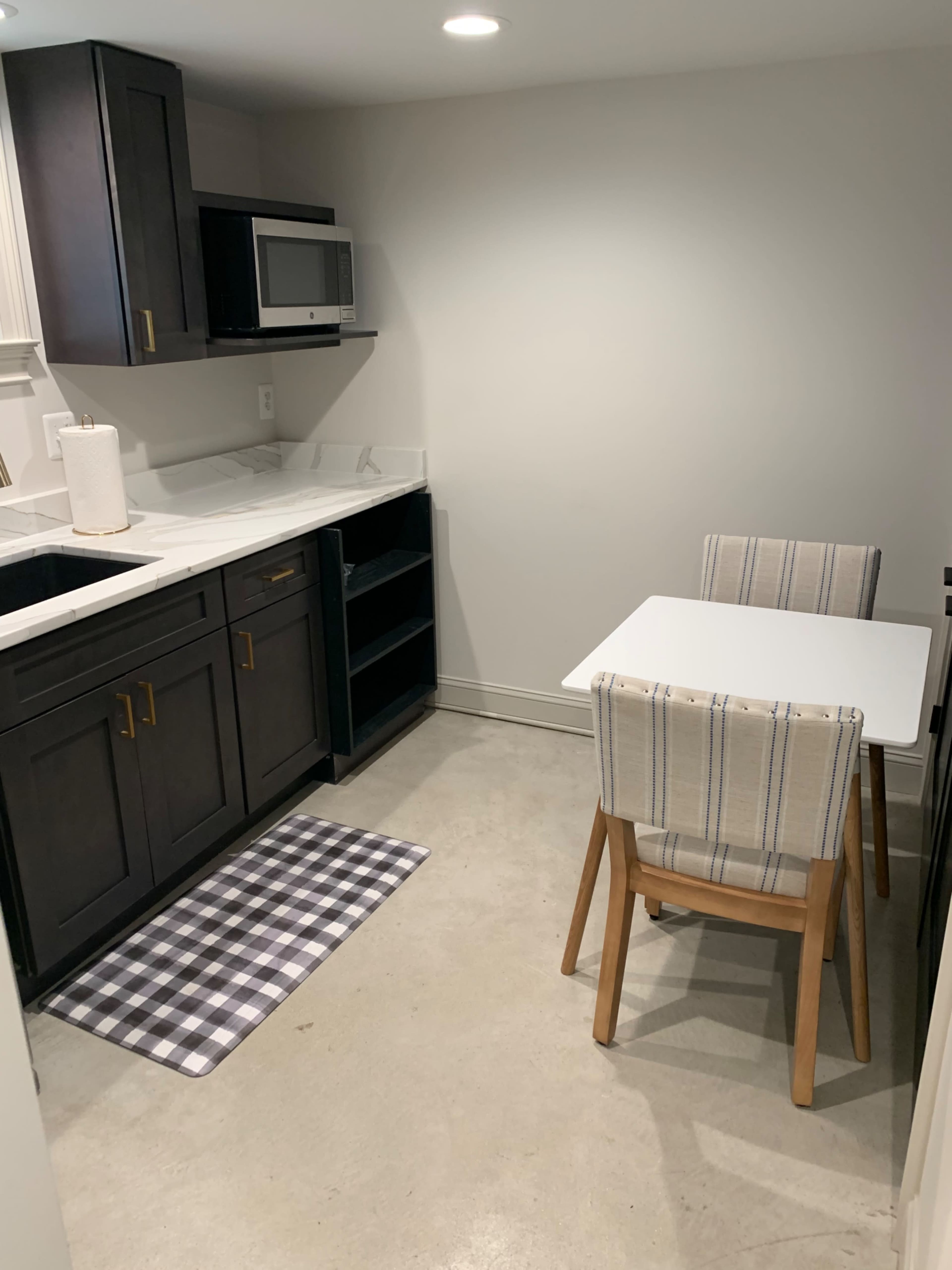 A compact kitchenette features dark cabinetry, a small dining table with two chairs, and a microwave on the counter.