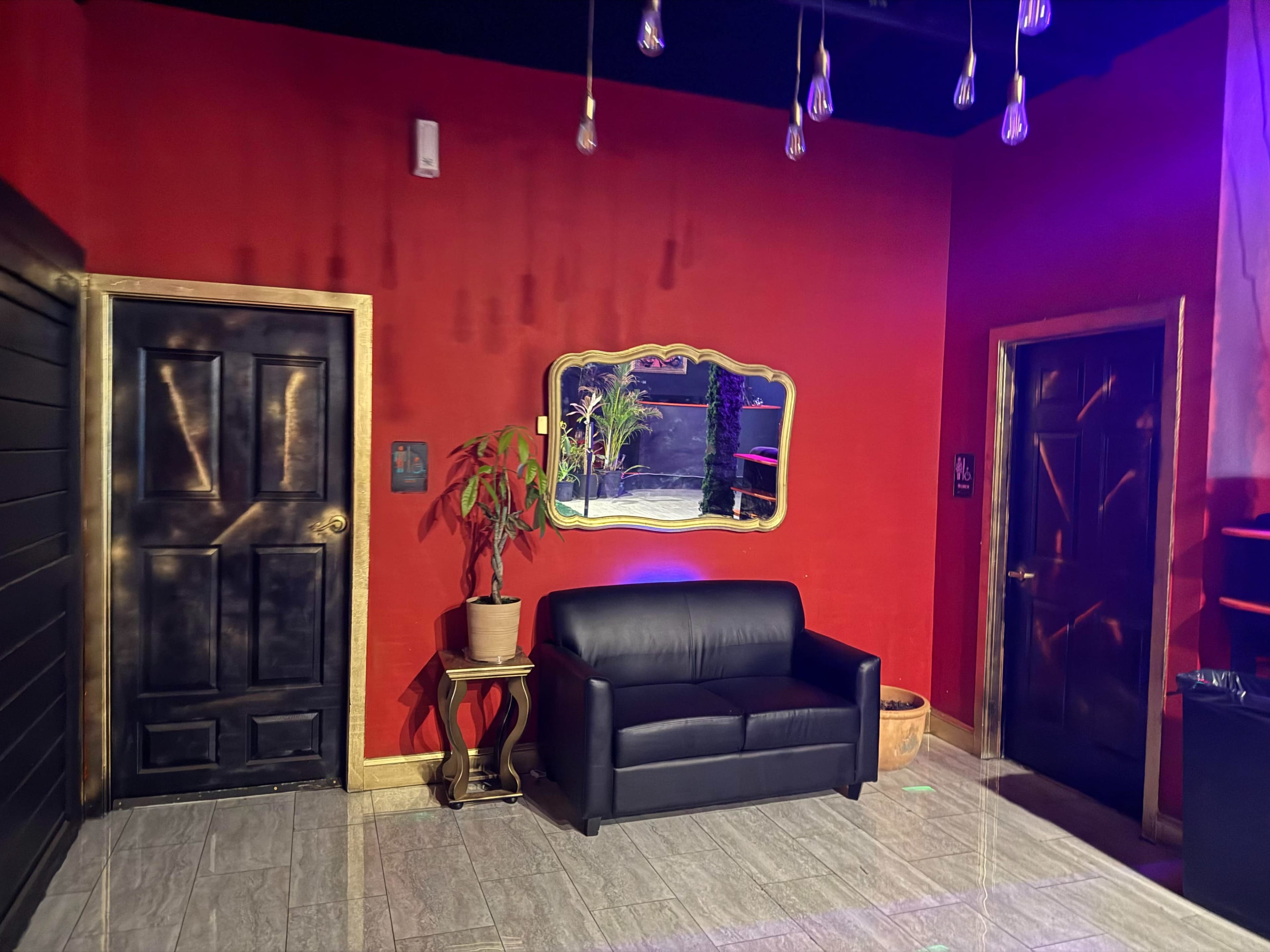 The image depicts a room with red walls, a black door, a gold-framed mirror, a black couch, and a door on the right.
