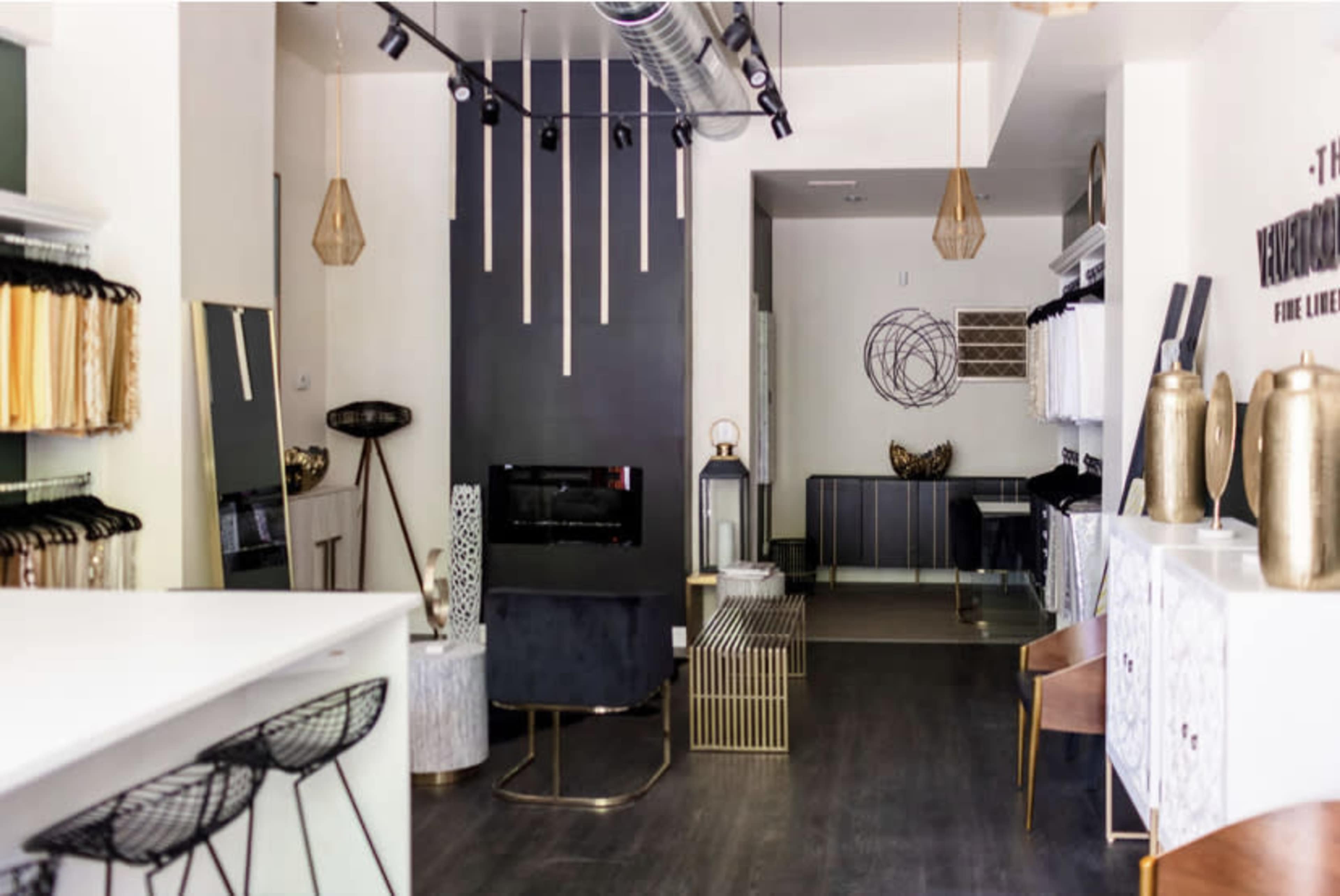 A modern retail space featuring a minimalist interior design with a mix of clothing racks, decorative items, and a stylish seating area.