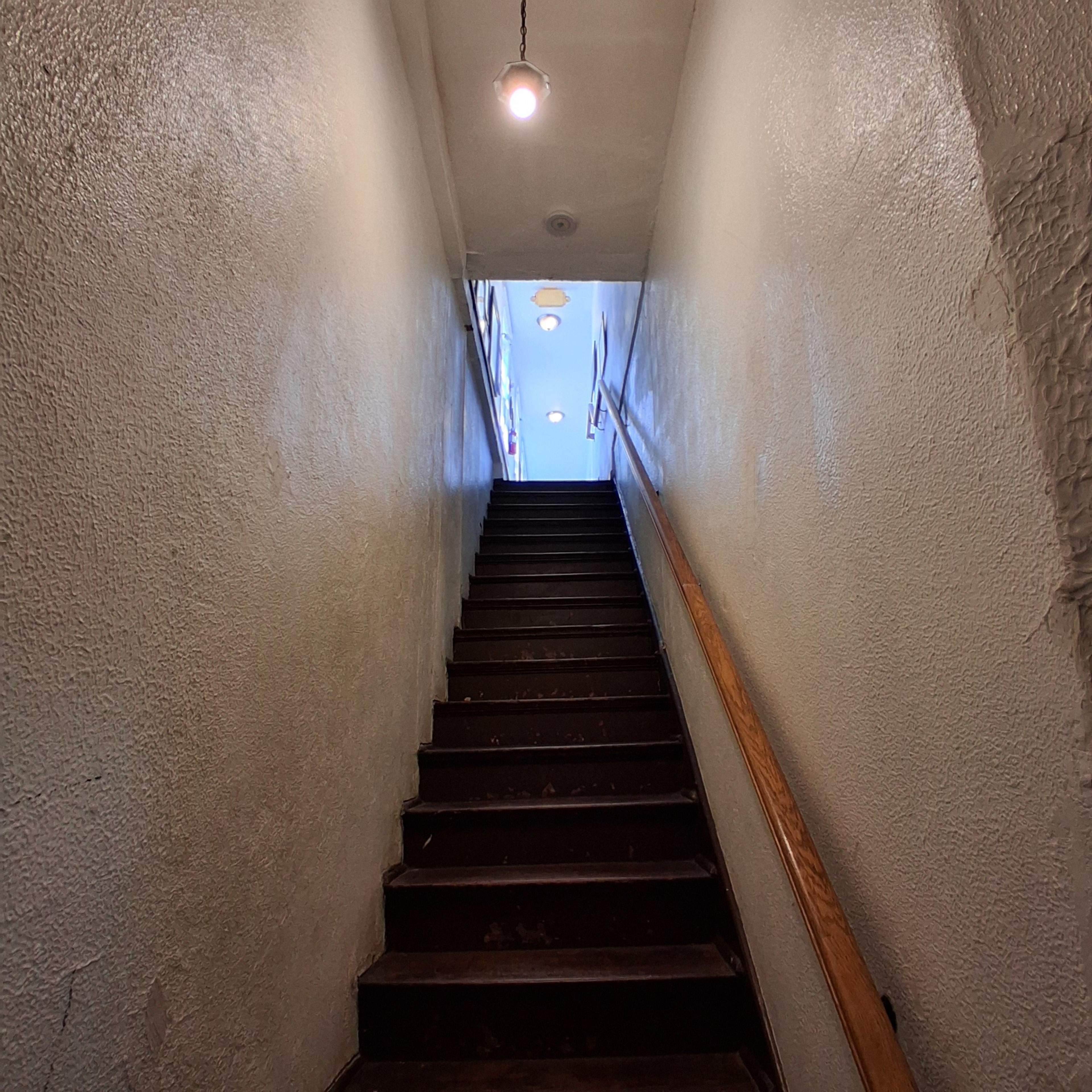 A dimly lit staircase leads upward to a bright opening at the top.