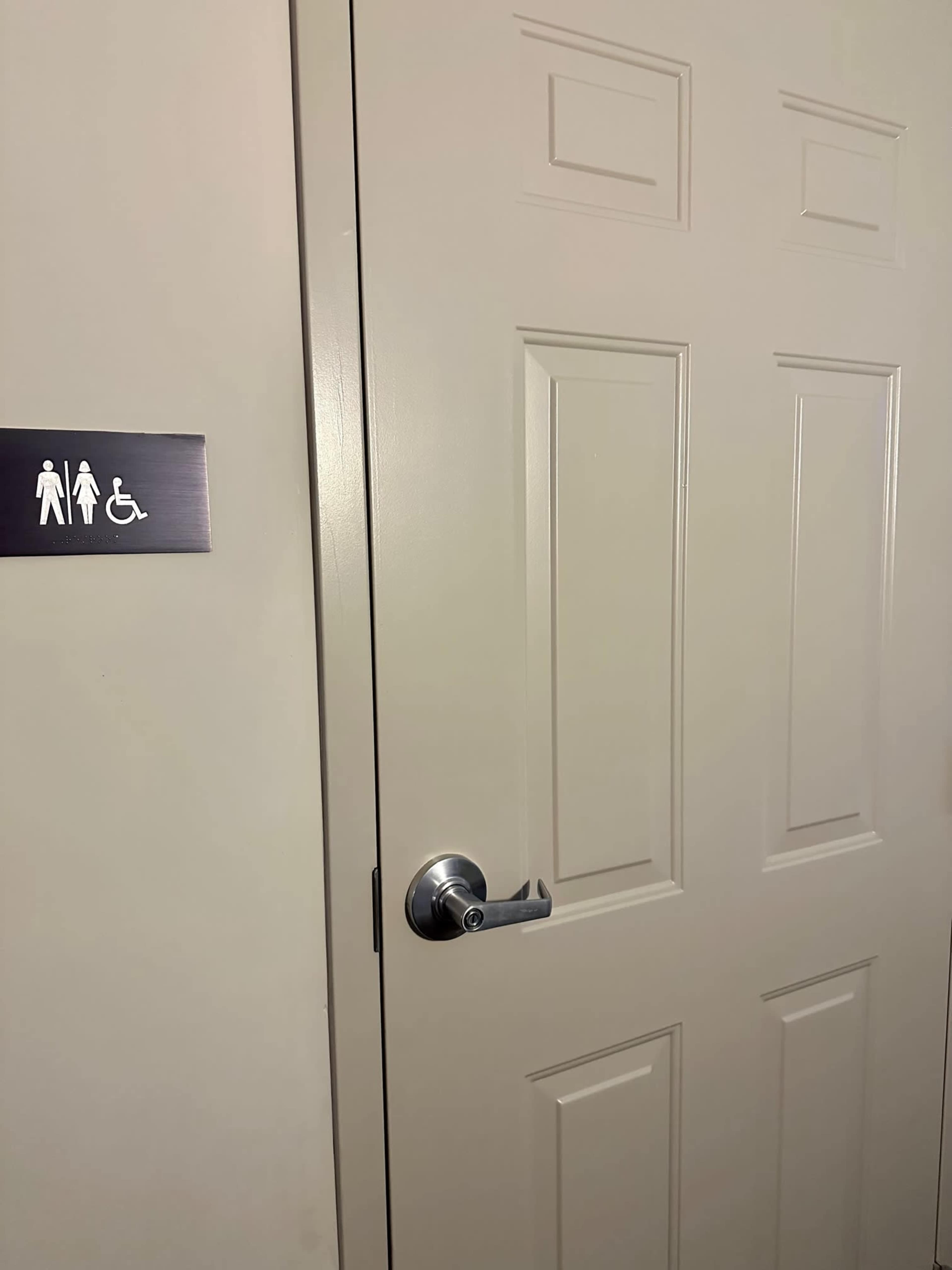 A closed door is shown with a sign indicating a restroom with accessible features.