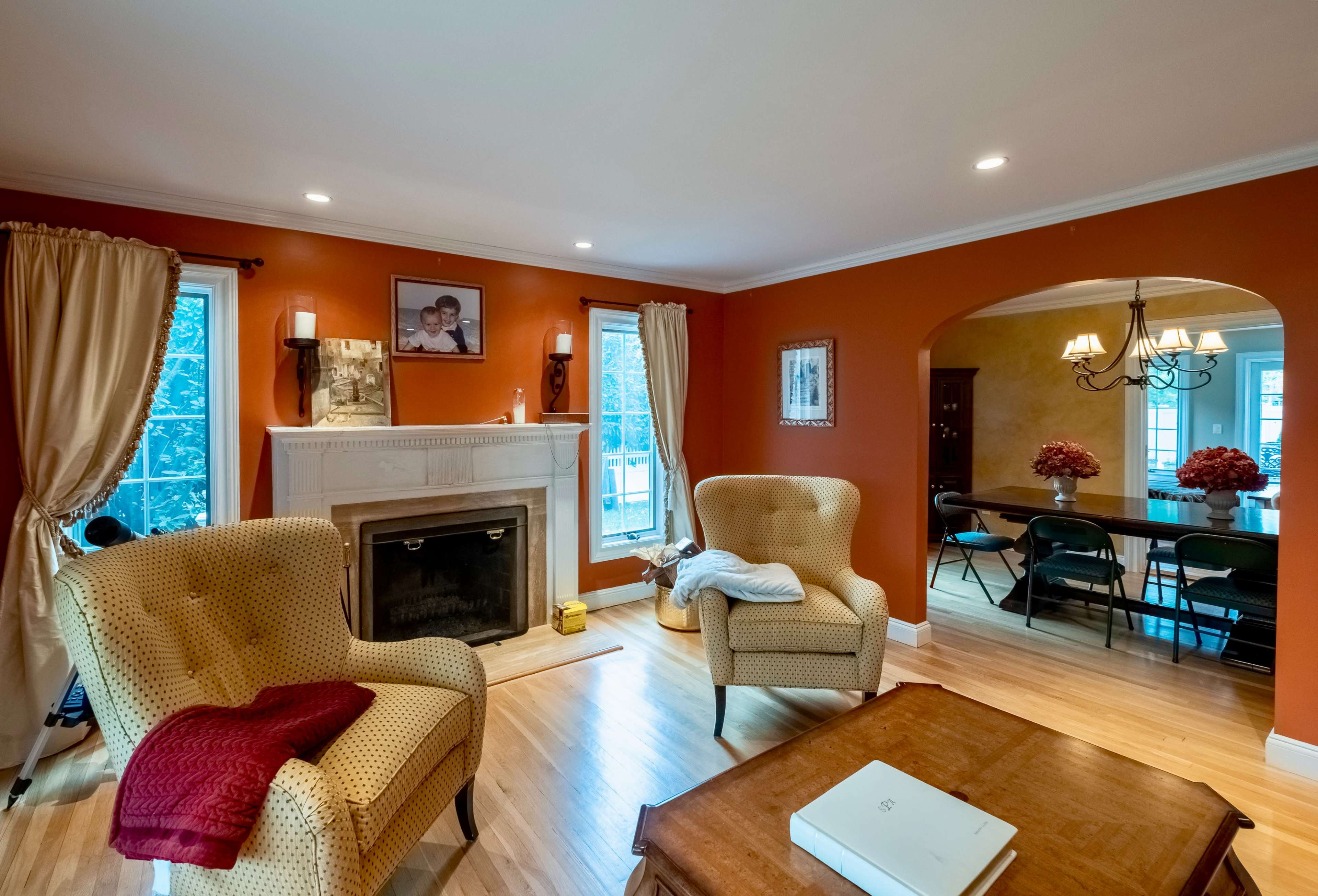 A living room with two upholstered armchairs, a fireplace, and a dining area featuring a black table and chairs.