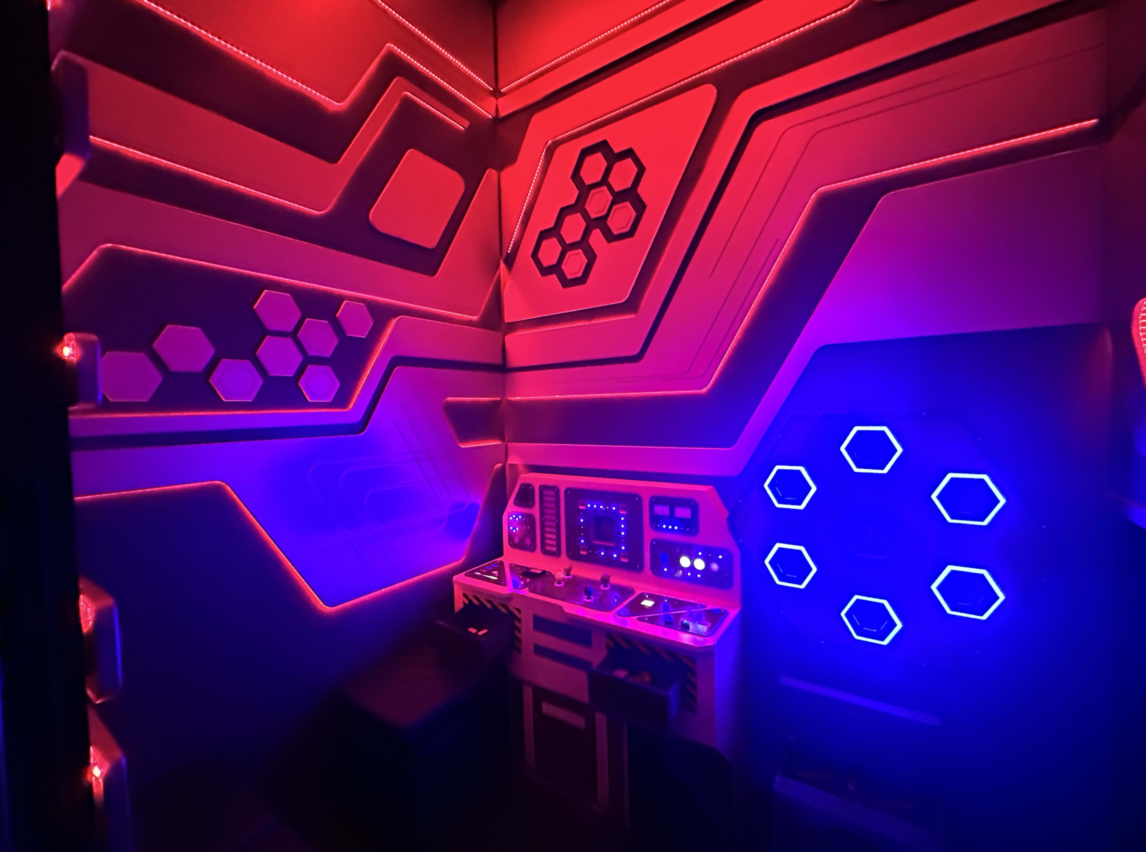 The image shows a futuristic control room with hexagonal patterns and colored lighting in red and blue.