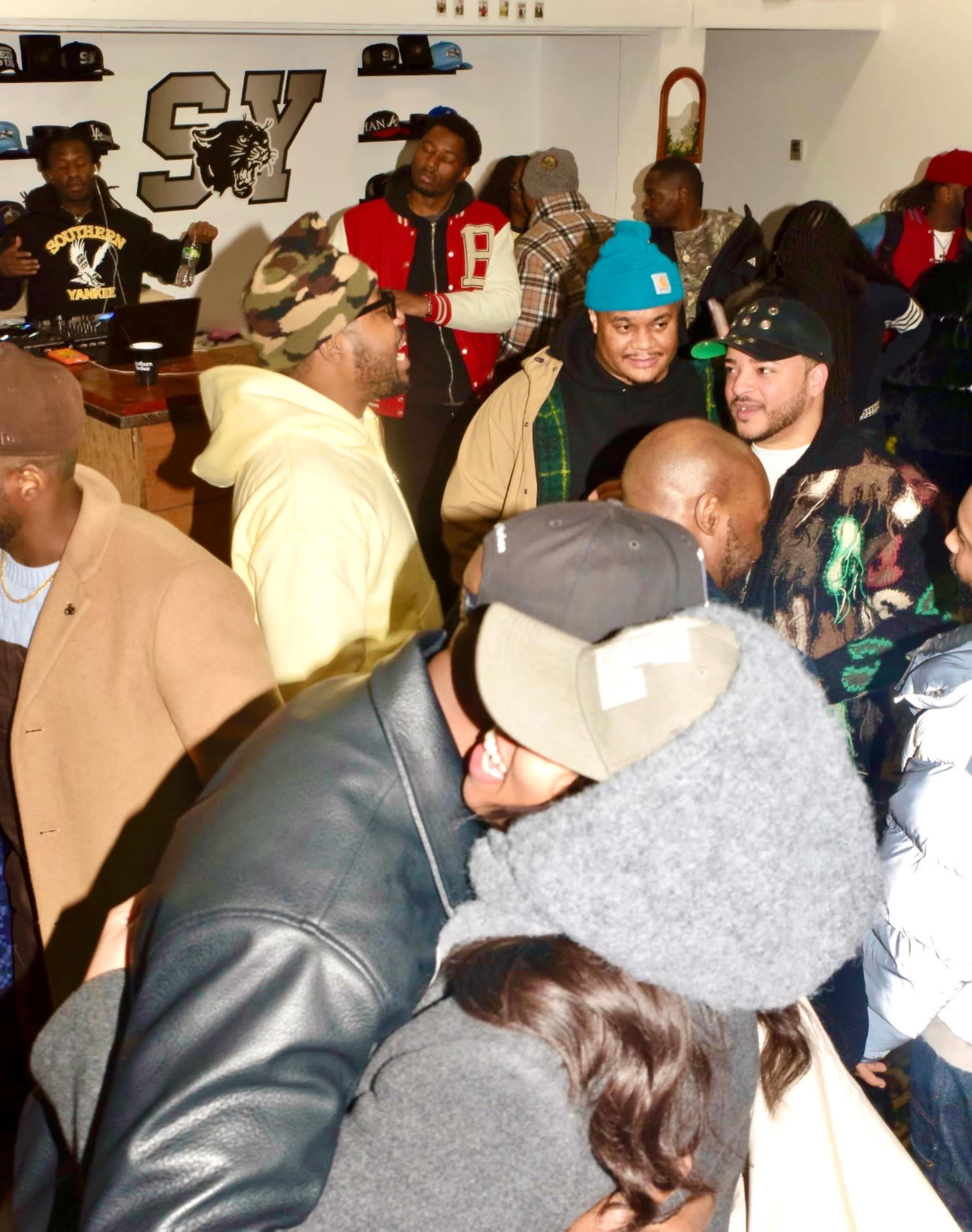 A crowded event features individuals socializing and interacting, with some people exchanging embraces and conversation.