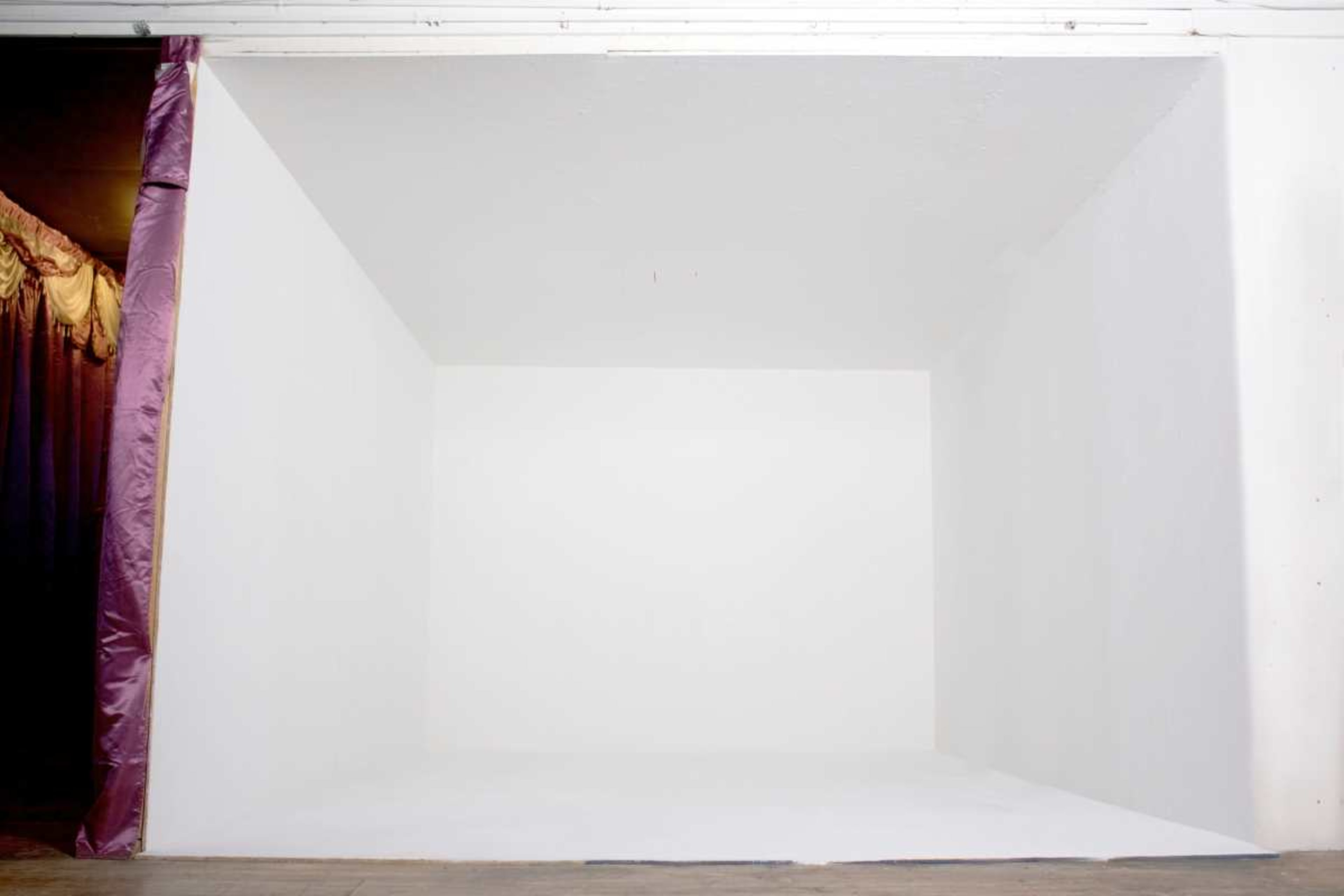The image shows a plain white room with four walls and no furniture or decorations.