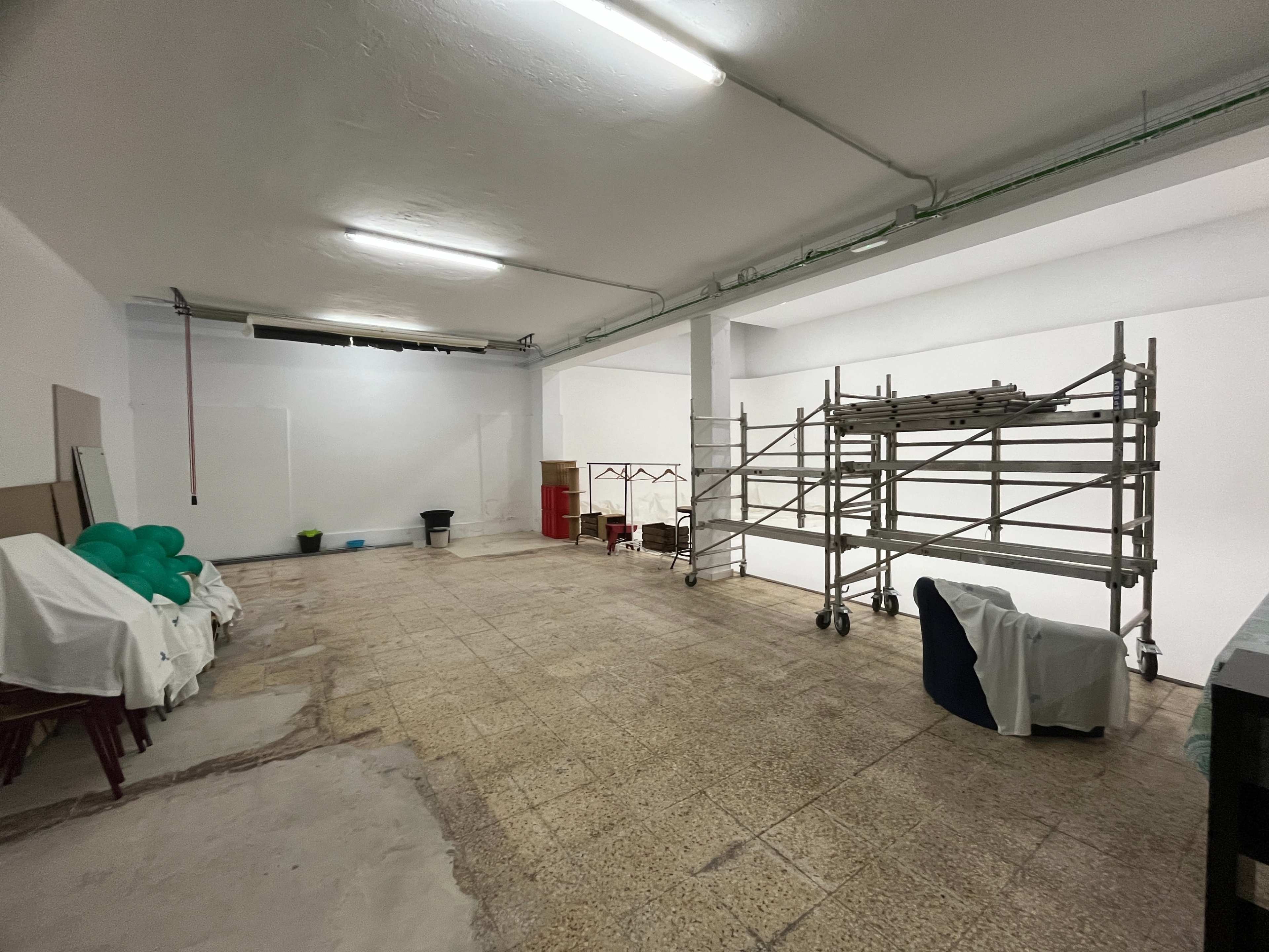 The image shows an empty room with tiled flooring, scaffolding on one side, and various objects covered with cloth scattered around.