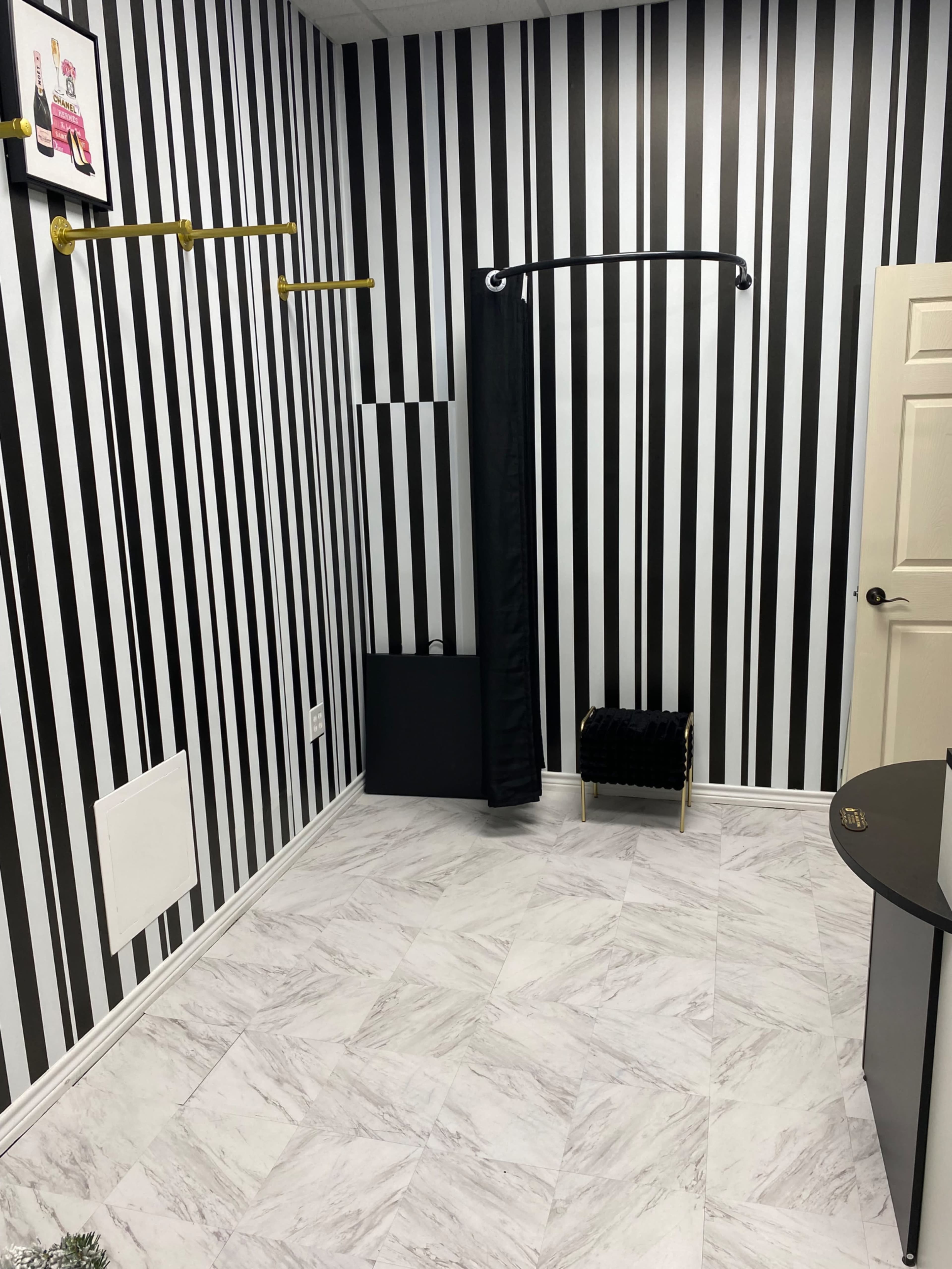 The image shows a room with vertical black and white striped walls, a black curtain, and a checkered floor.