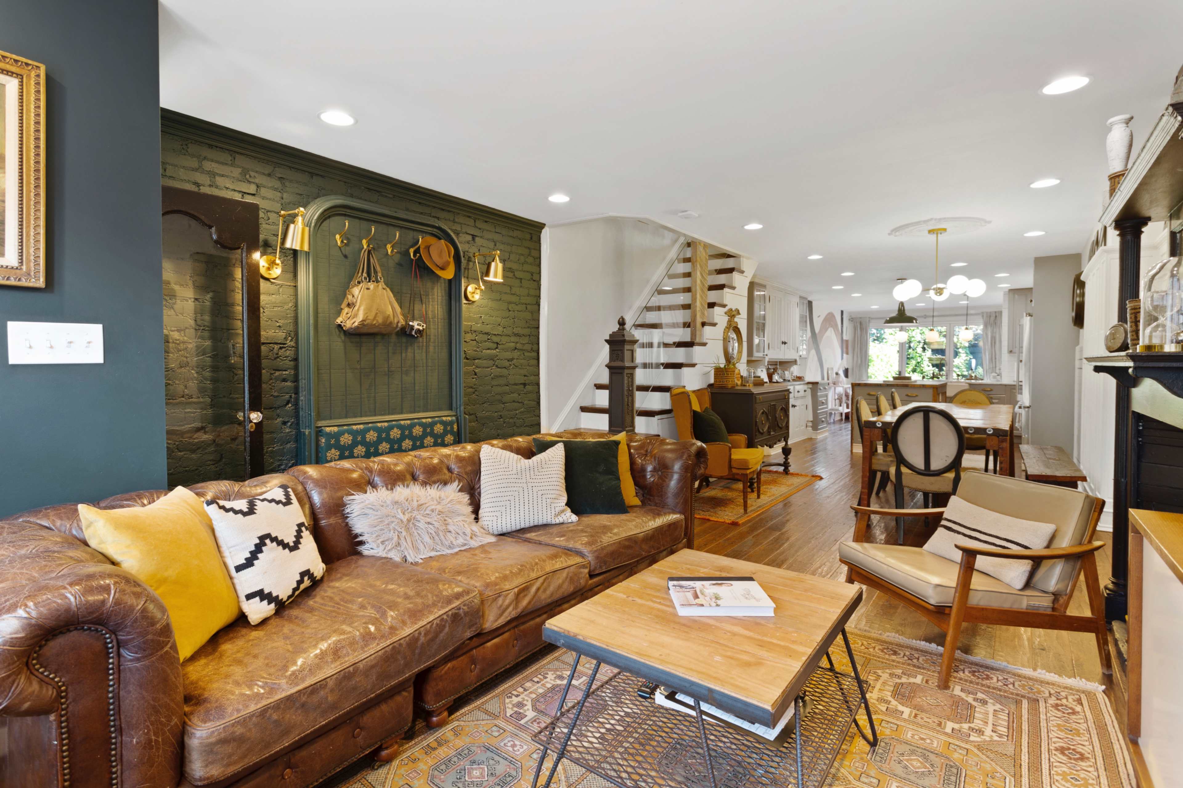 The room features a cozy living area with a brown leather sofa, a wooden coffee table, and a staircase leading to the upper level.