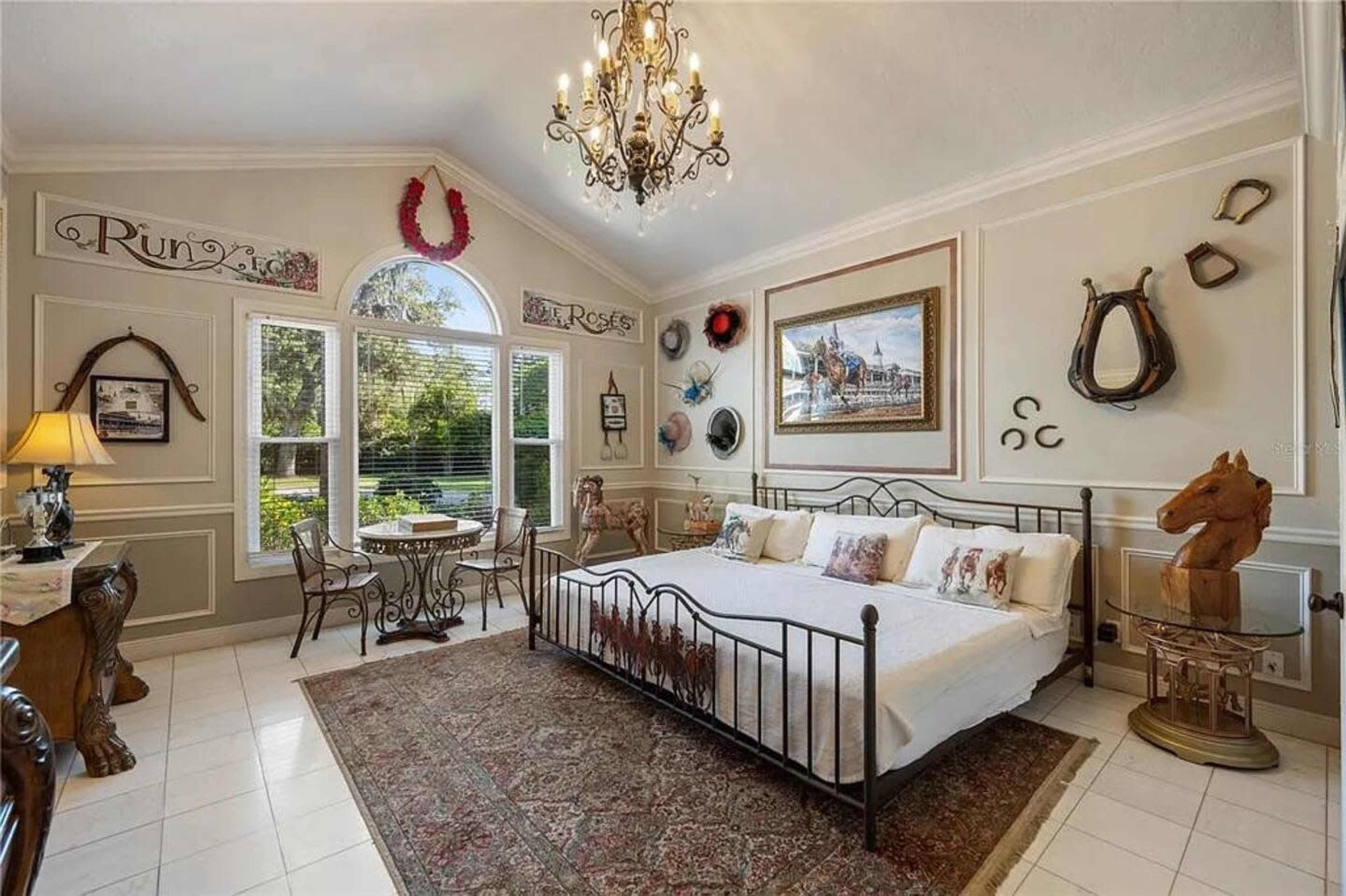 The room features a bed with a decorative iron frame, a large area rug, and mounted horse-themed decor on the walls.