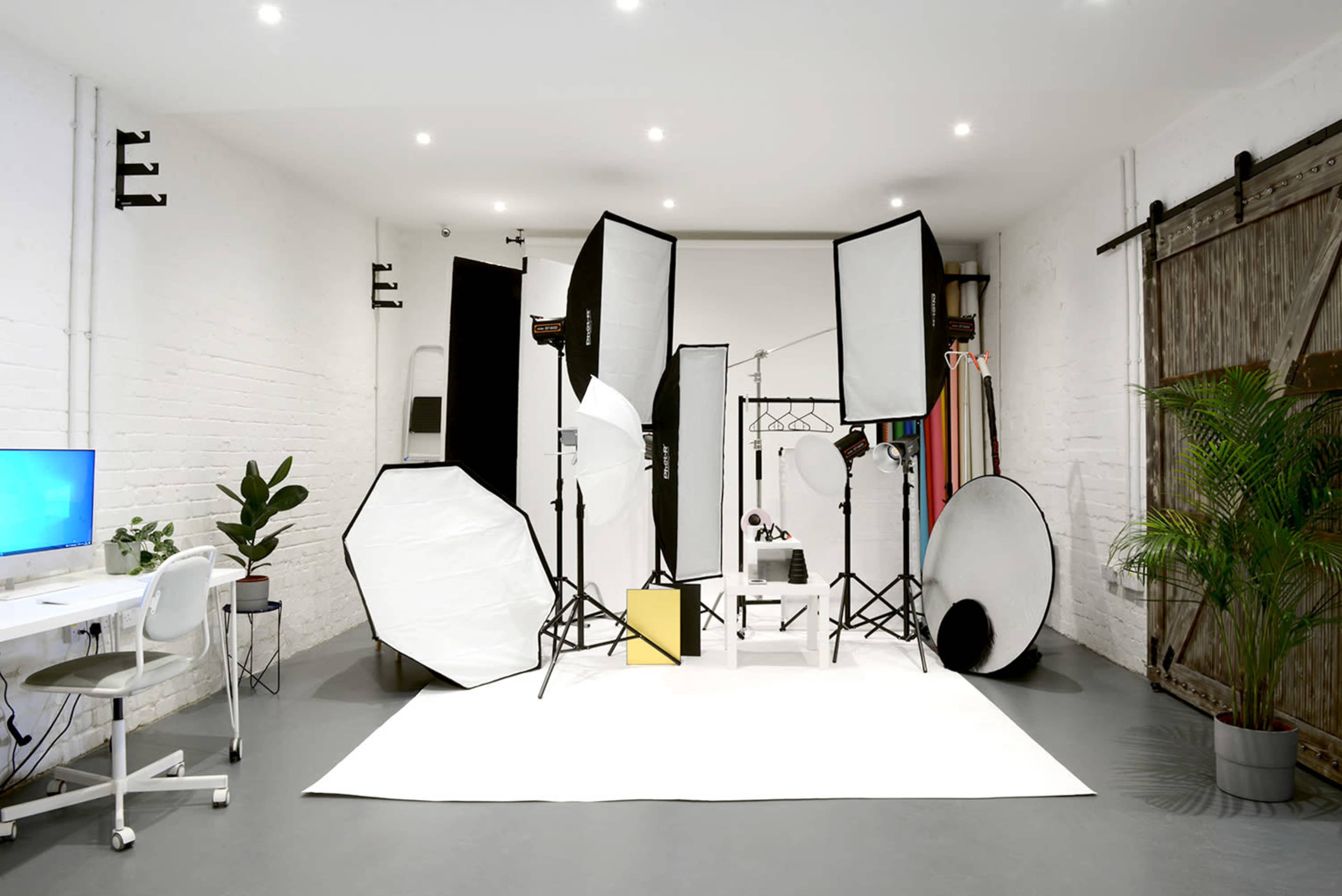 A photography studio is set up with various lighting equipment and backdrops arranged on a white backdrop.
