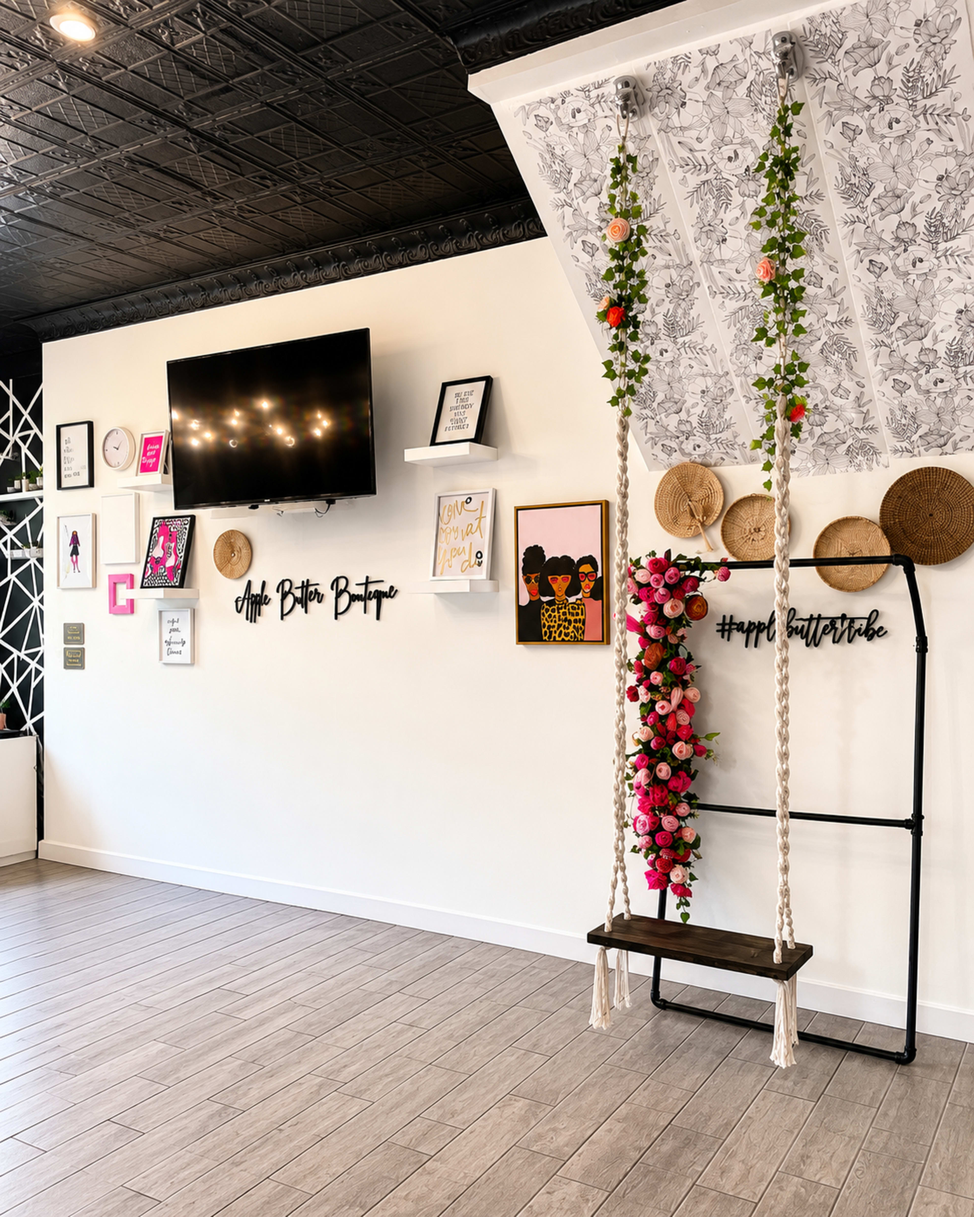 The image depicts a stylish interior wall featuring a decorative swing adorned with flowers, framed art, and various wall hangings.