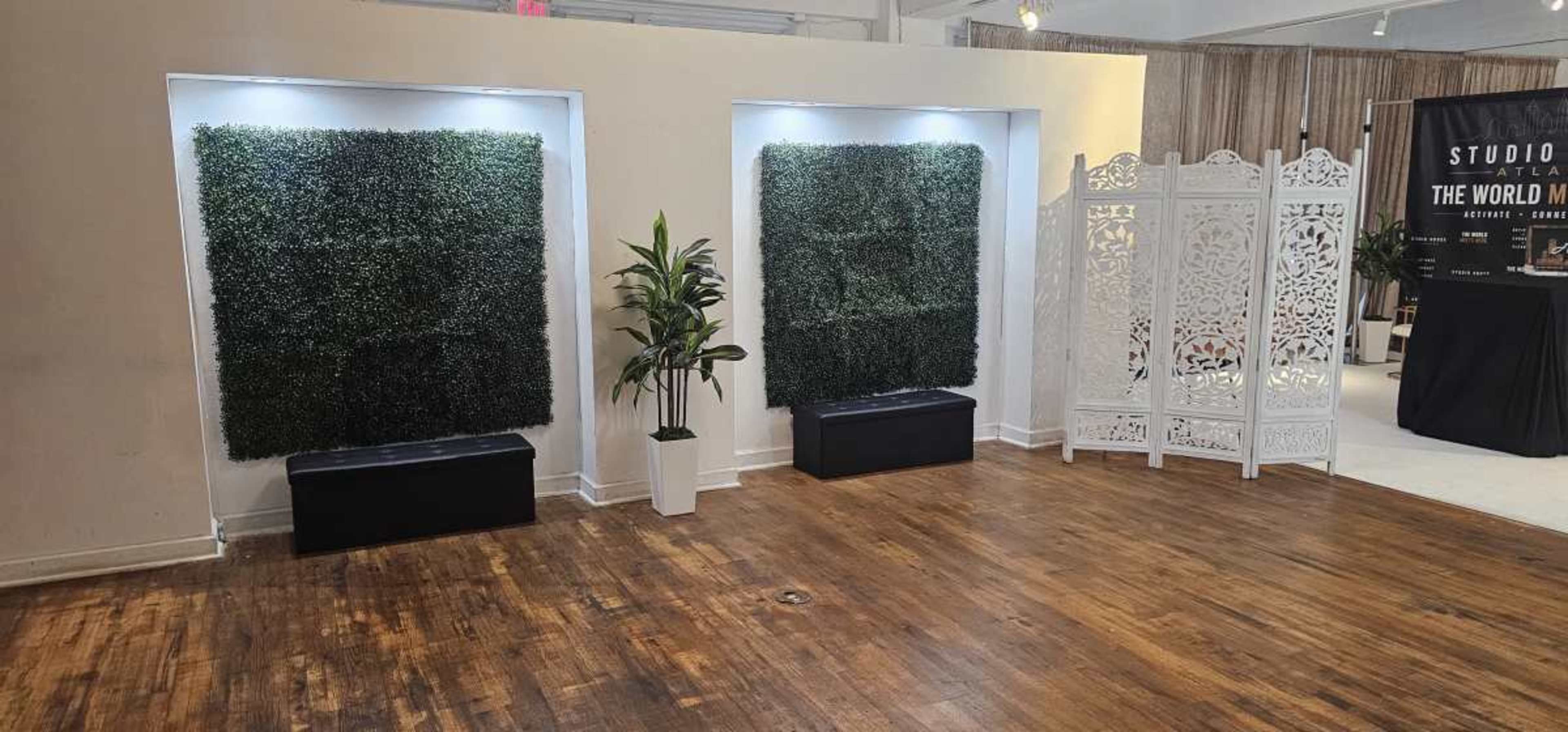 The image shows an indoor space with two vertical greenery planters on the walls, a decorative screen on the right, and a wooden floor.