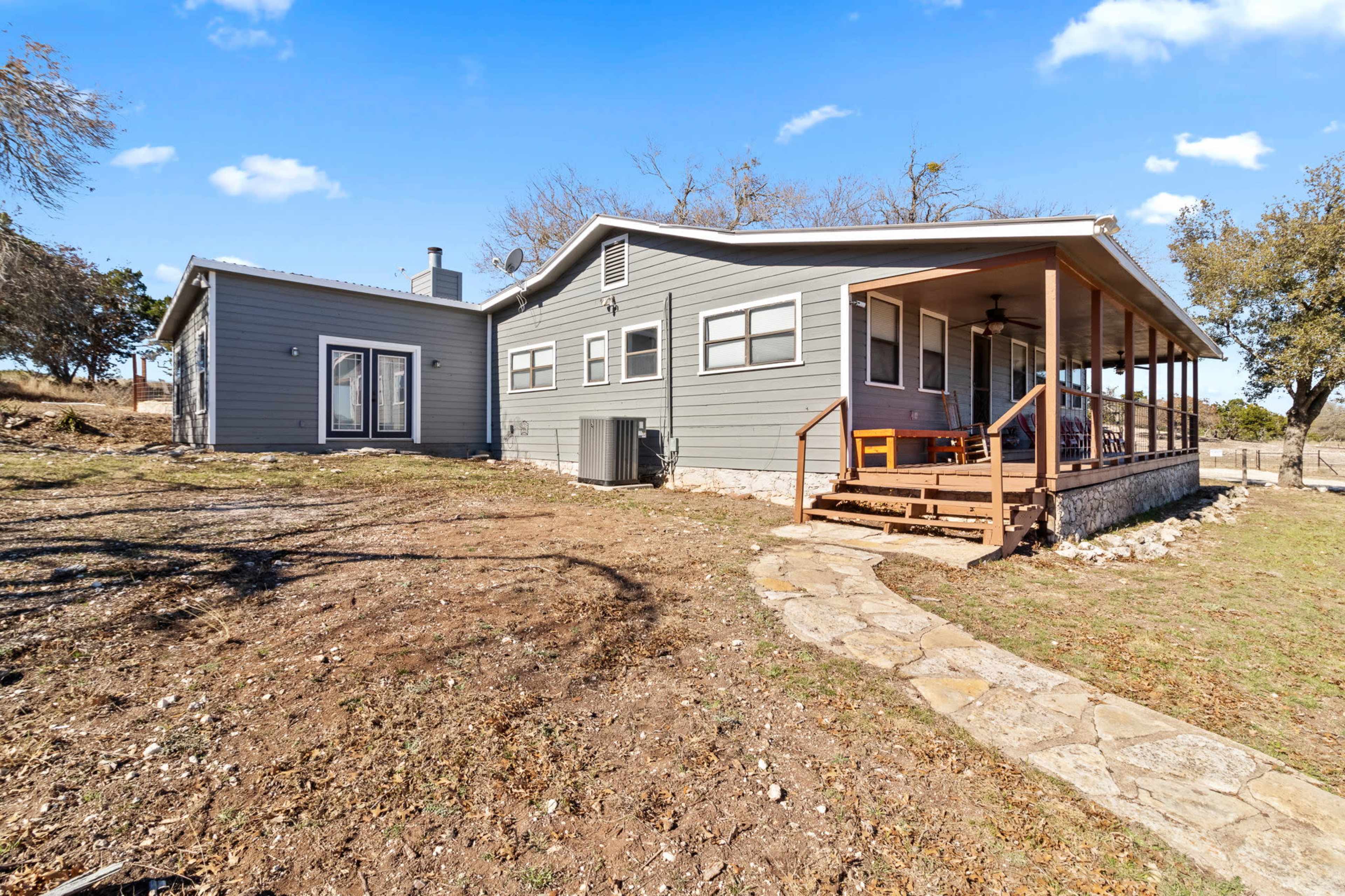 A single-story house with a covered porch and stone pathway is set on a grassy lot.