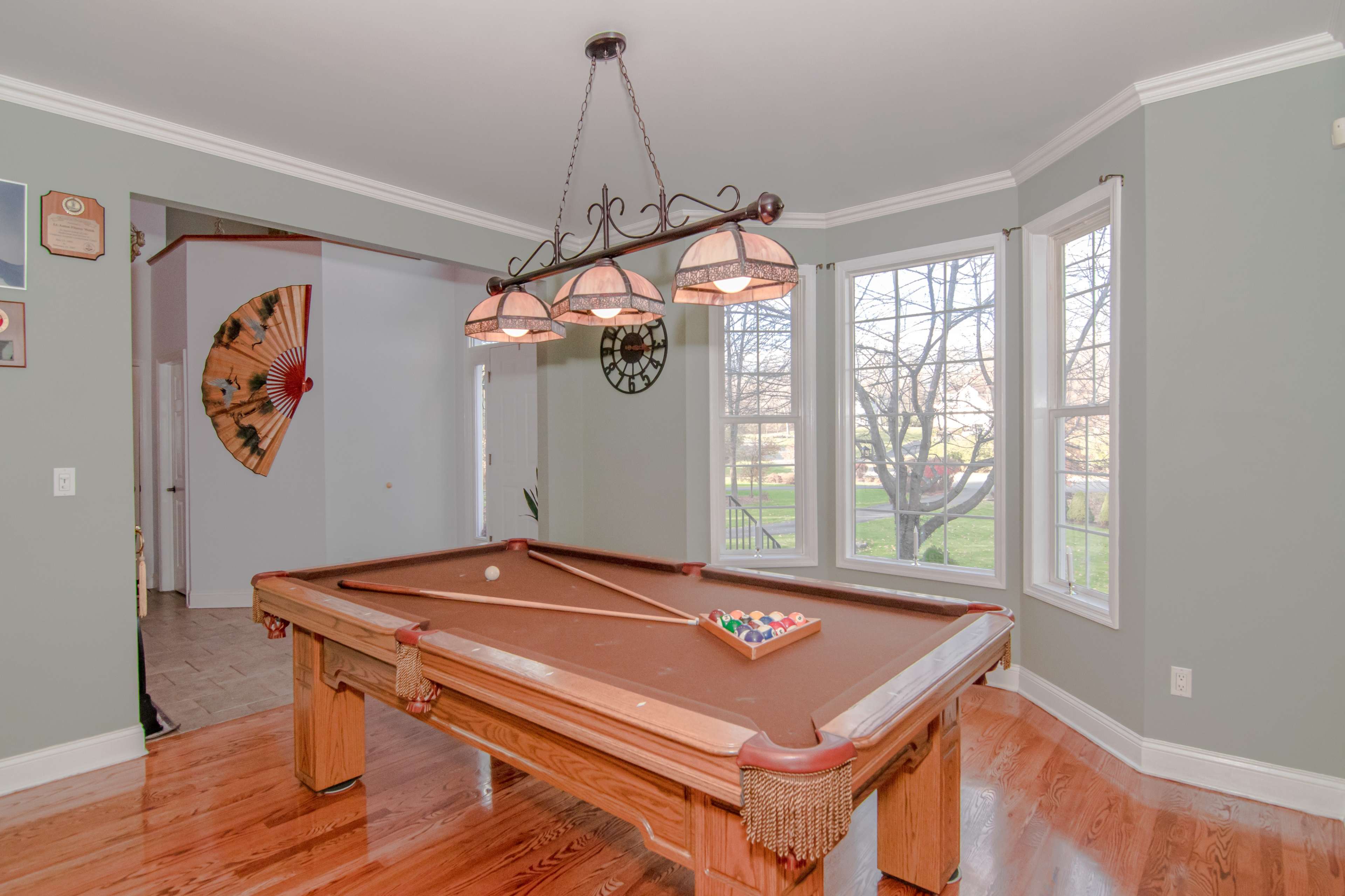 A billiard table in a brightly lit room with large windows and decorative light fixtures.