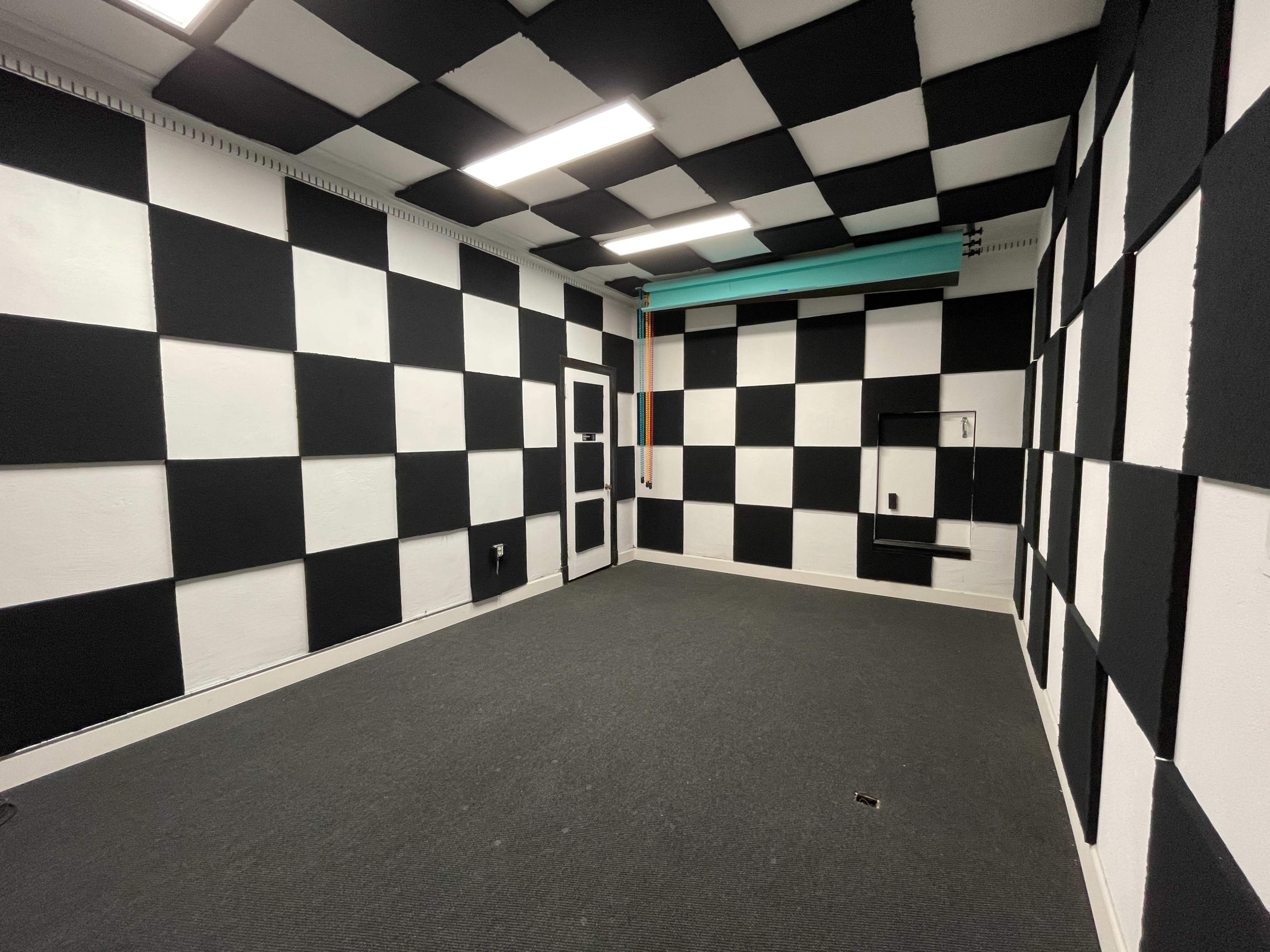 A room with a checkered black and white wall design and gray carpet.