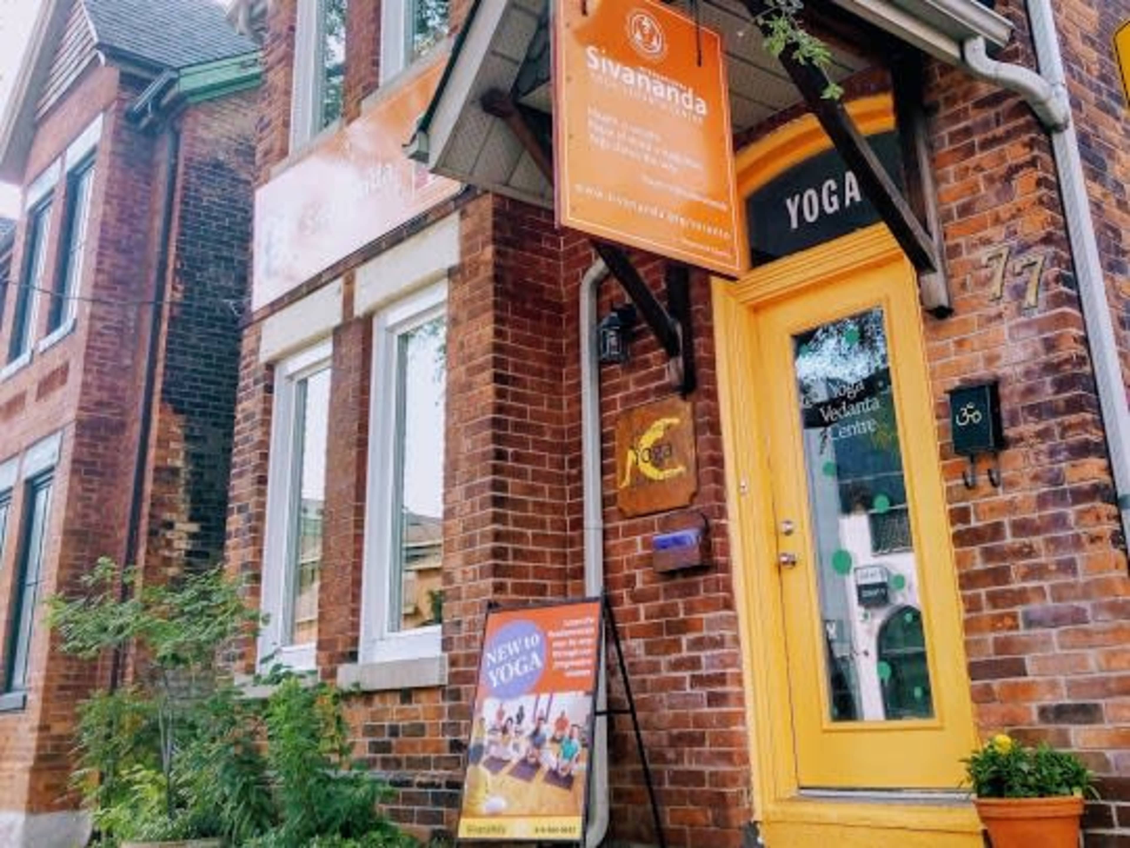 A brick building with bright orange signage marks the entrance to a yoga center called Sivananda.