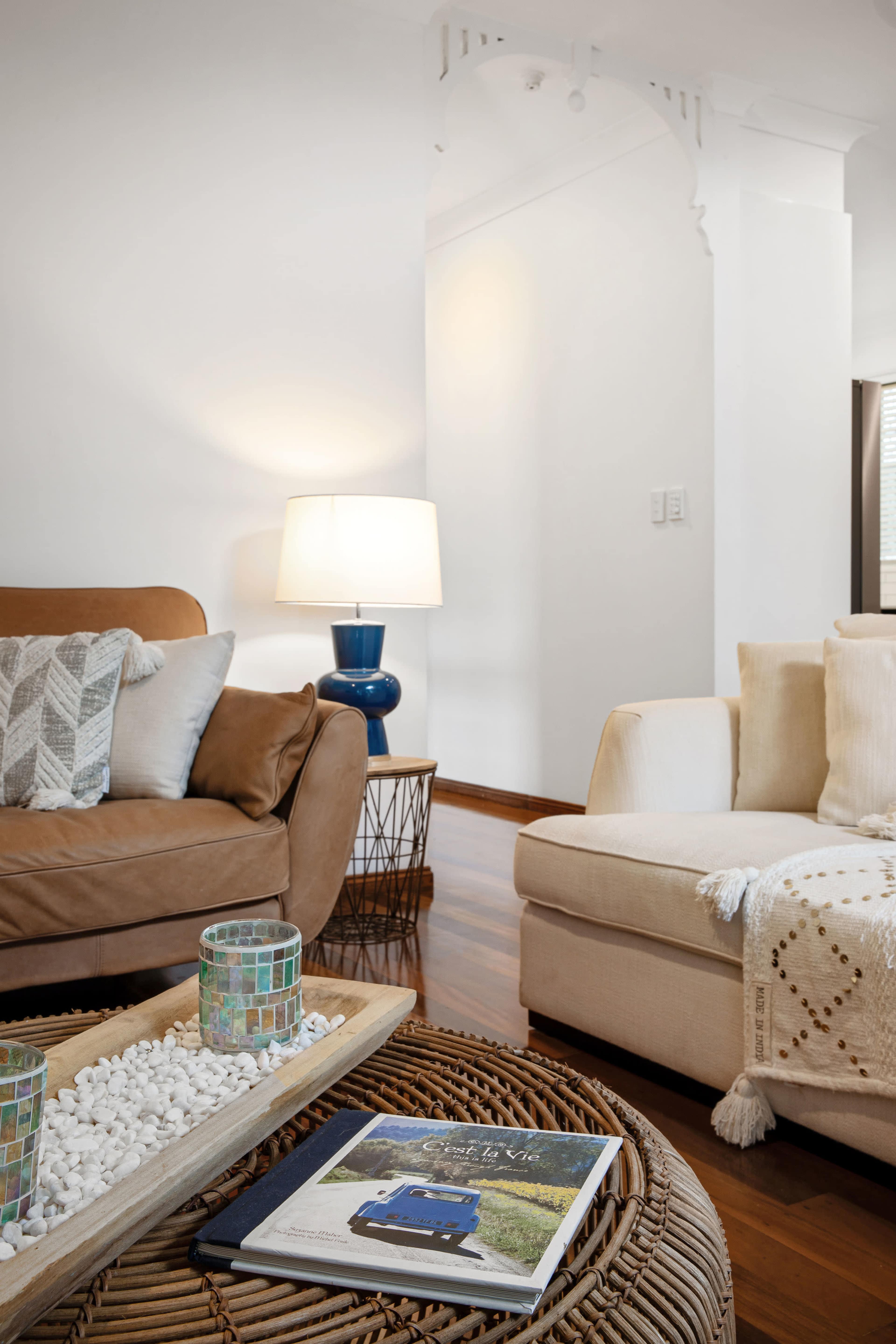 A cozy living room with two sofas, a coffee table made of woven material, and a lamp on a side table.