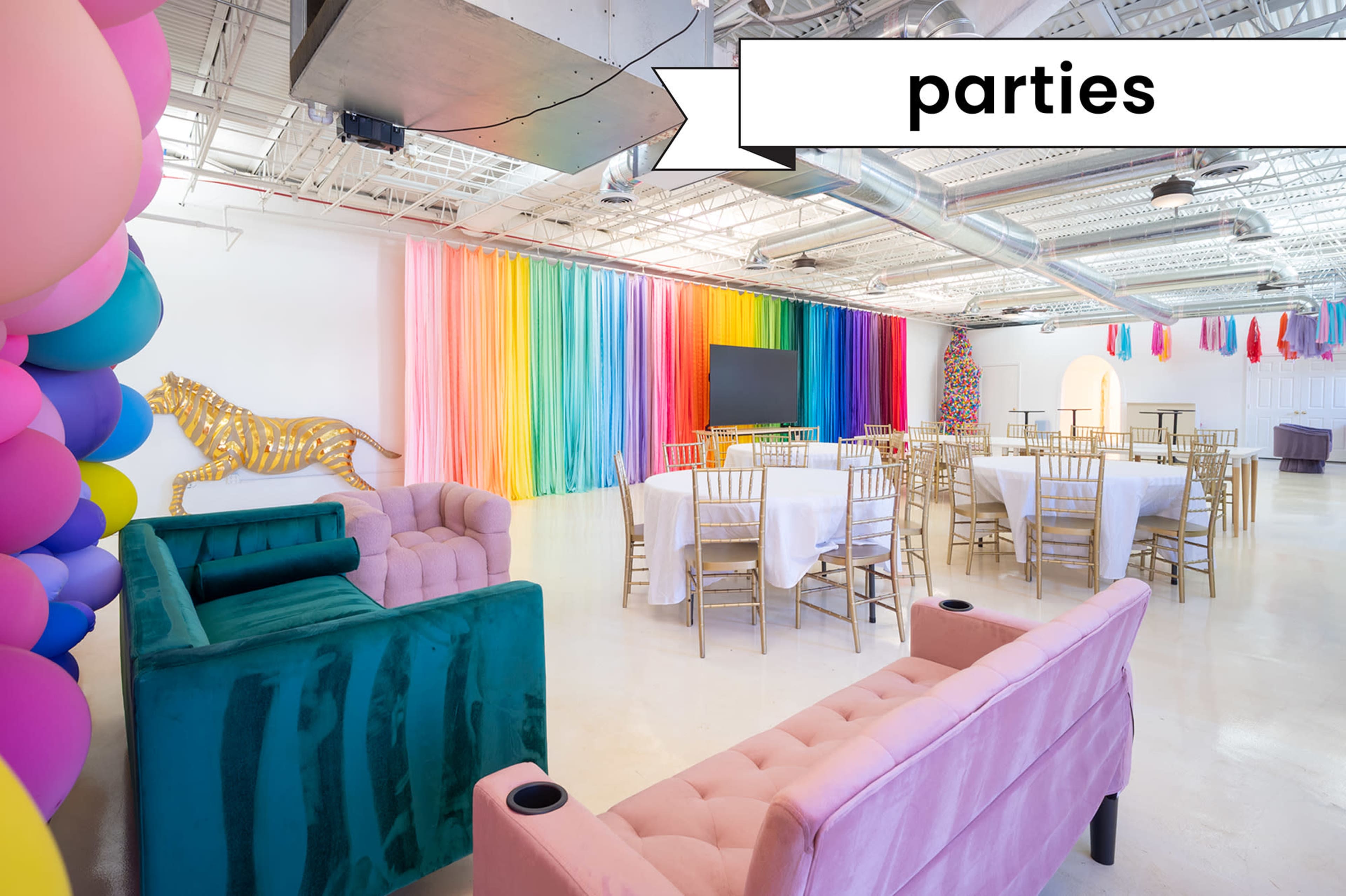 The image shows a decorated event space with a rainbow curtain backdrop, gold-accented furniture, and multiple tables set for a gathering.