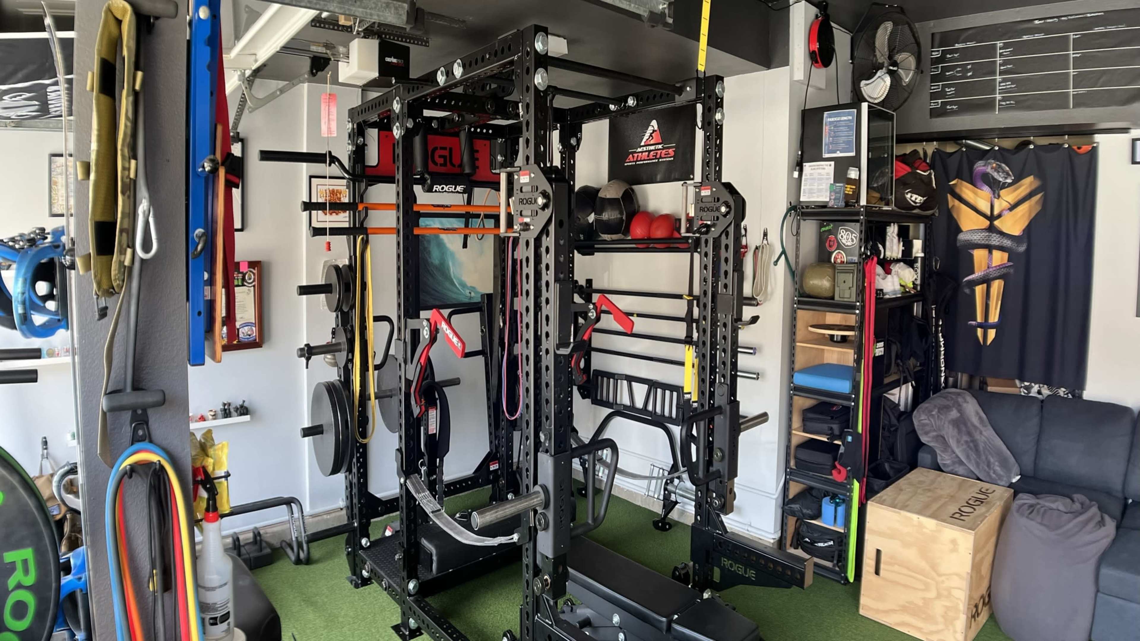 The image shows a well-equipped home gym featuring a power rack, various weights, and exercise accessories organized on shelves and walls.