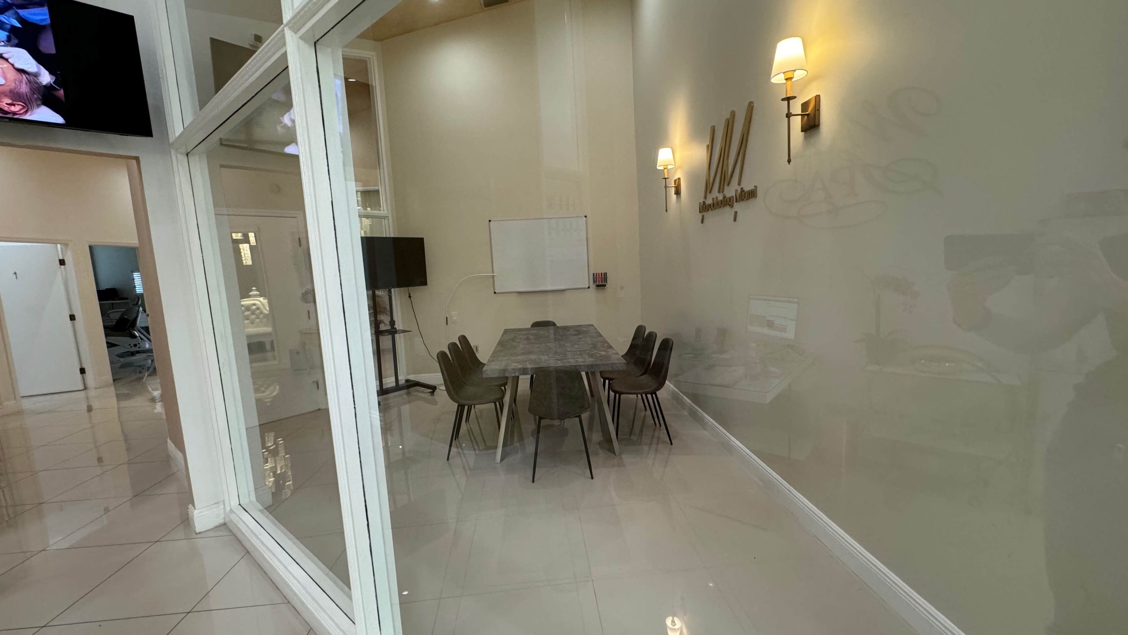 The image shows a modern conference room with a marble table surrounded by six chairs, and large windows letting in natural light.
